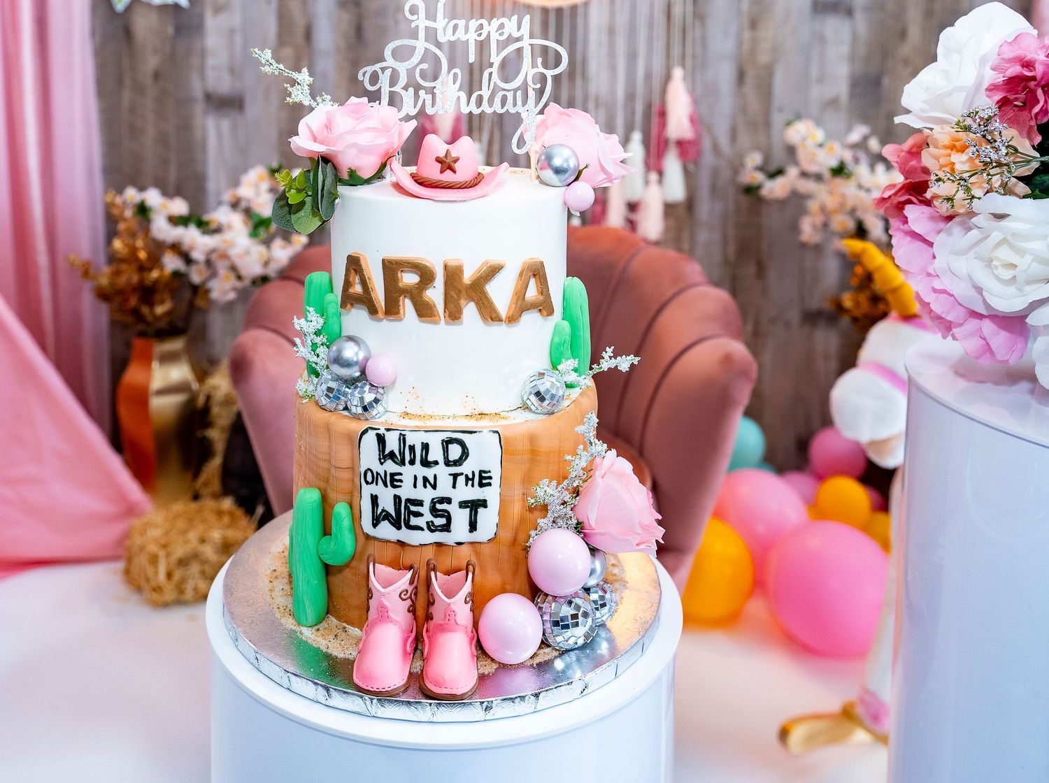 A western-themed birthday cake decorated with cactus and 'Wild One West' signage.