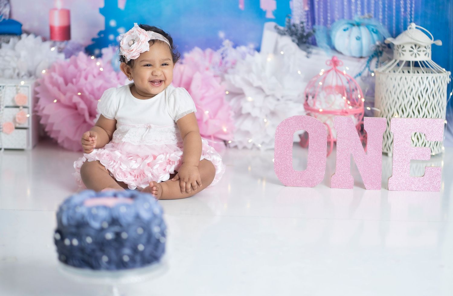 Pink and white themed birthday setup with decorative lanterns and castle backdrop.