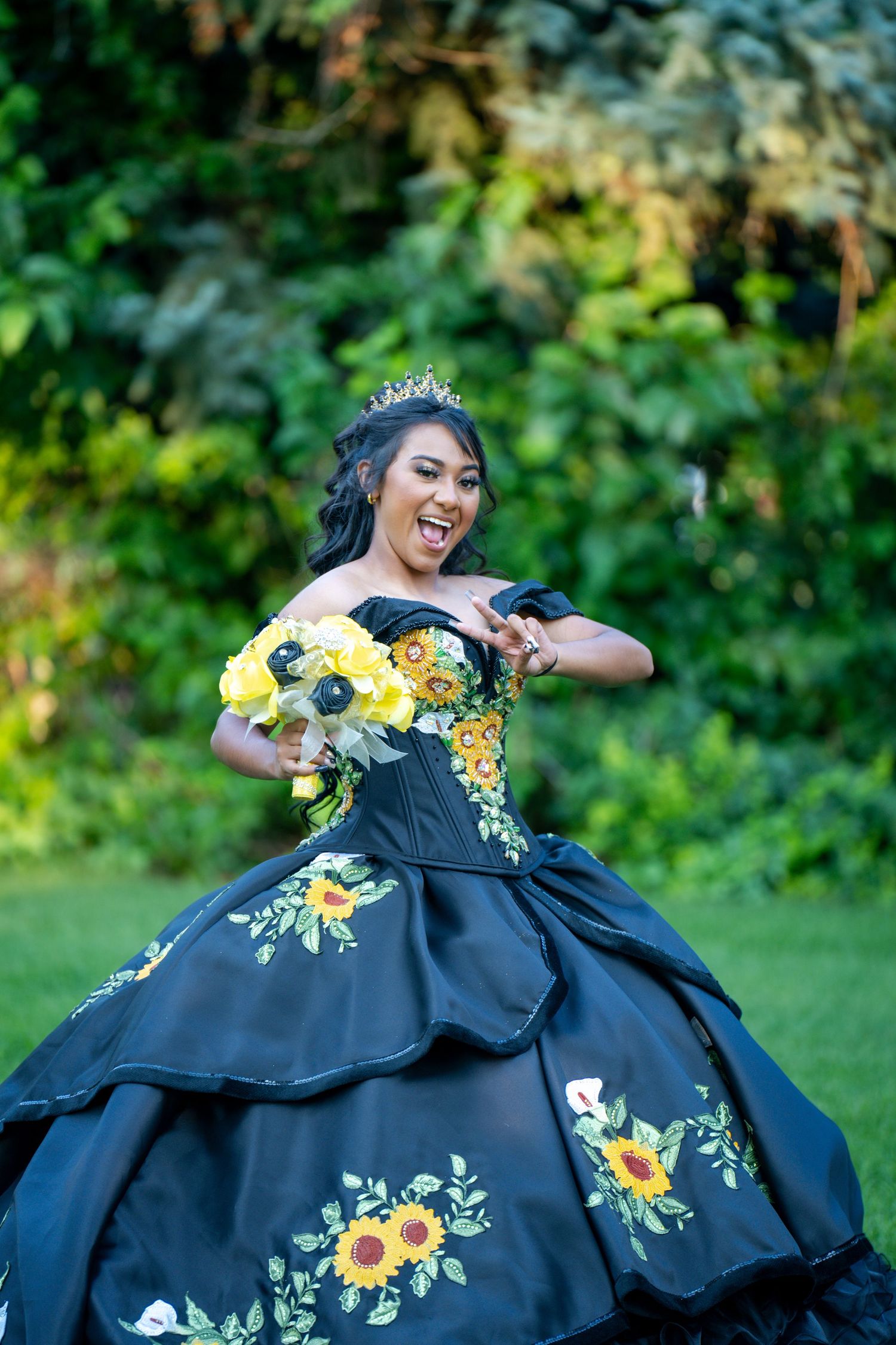 Elegant ballgown with yellow floral embroidery showcased in outdoor garden setting.