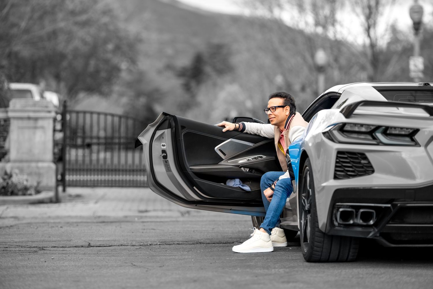 A sporty white car with open door highlighting modern design and luxury details against a monochromatic background.