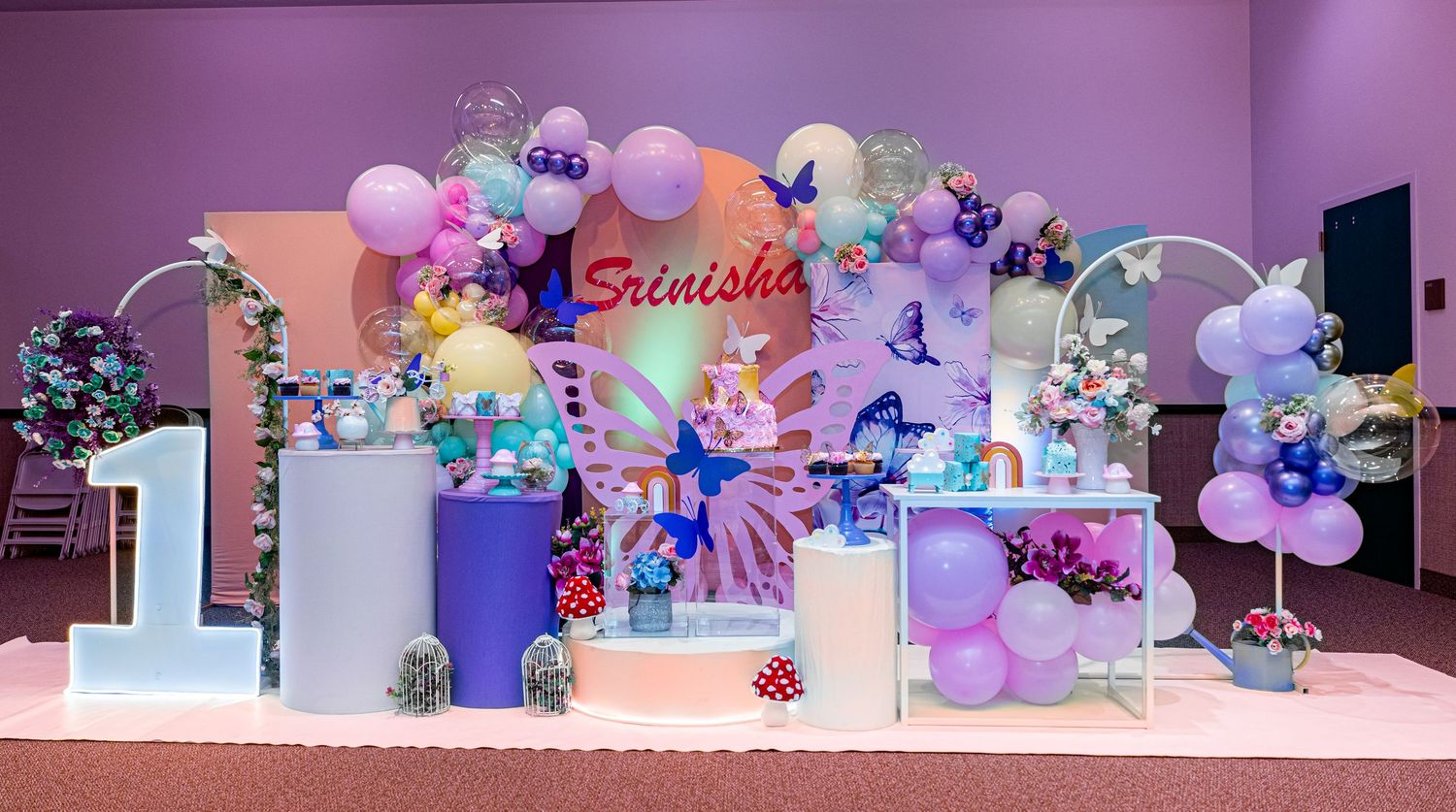 Elegant party backdrop with pastel balloon garland and floral decorations.