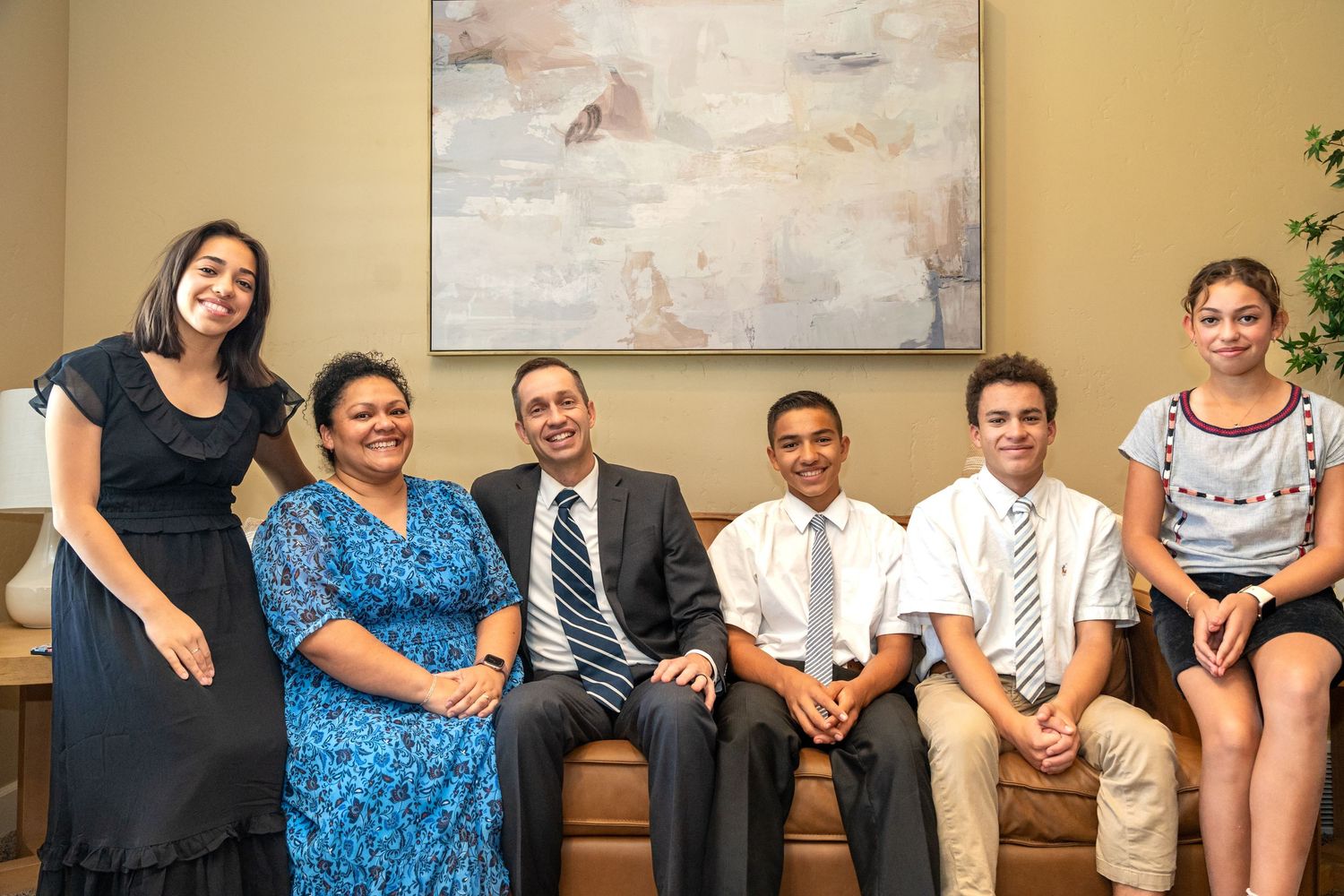 Professional group photo of diverse team members seated on a couch in business attire.