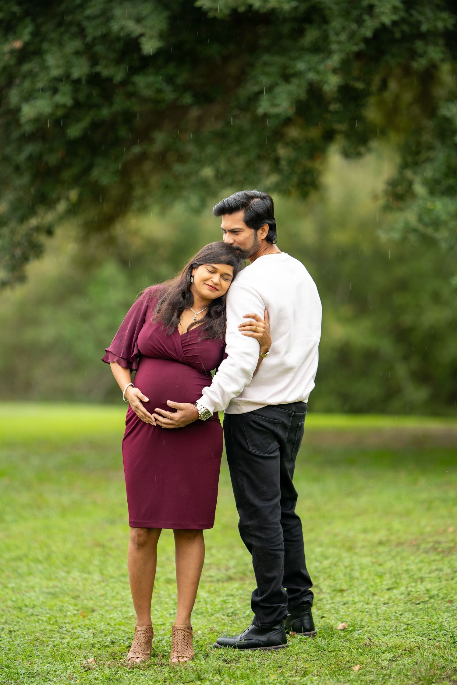 Intimate outdoor maternity portrait in natural setting with soft lighting.