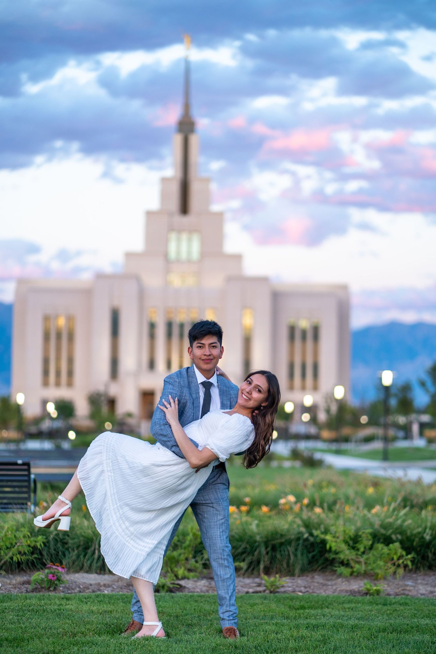 Romantic couple pose in front of Mormon temple at sunset.