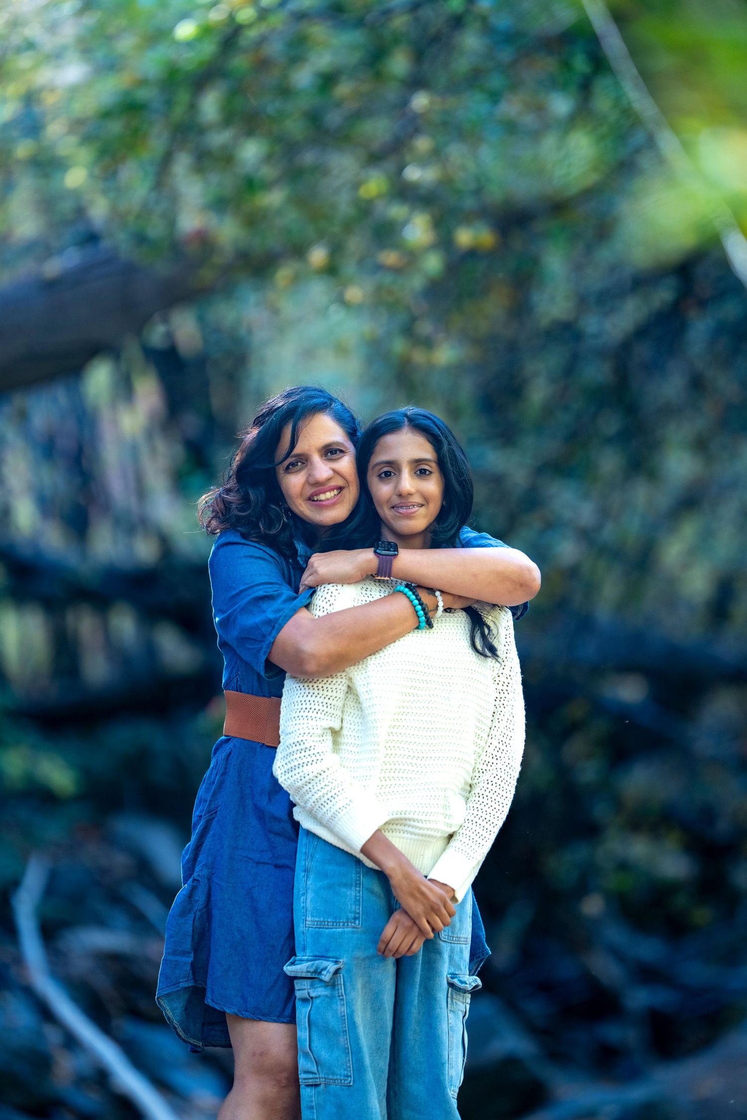 Two people sharing warm embrace outdoors with forest background.