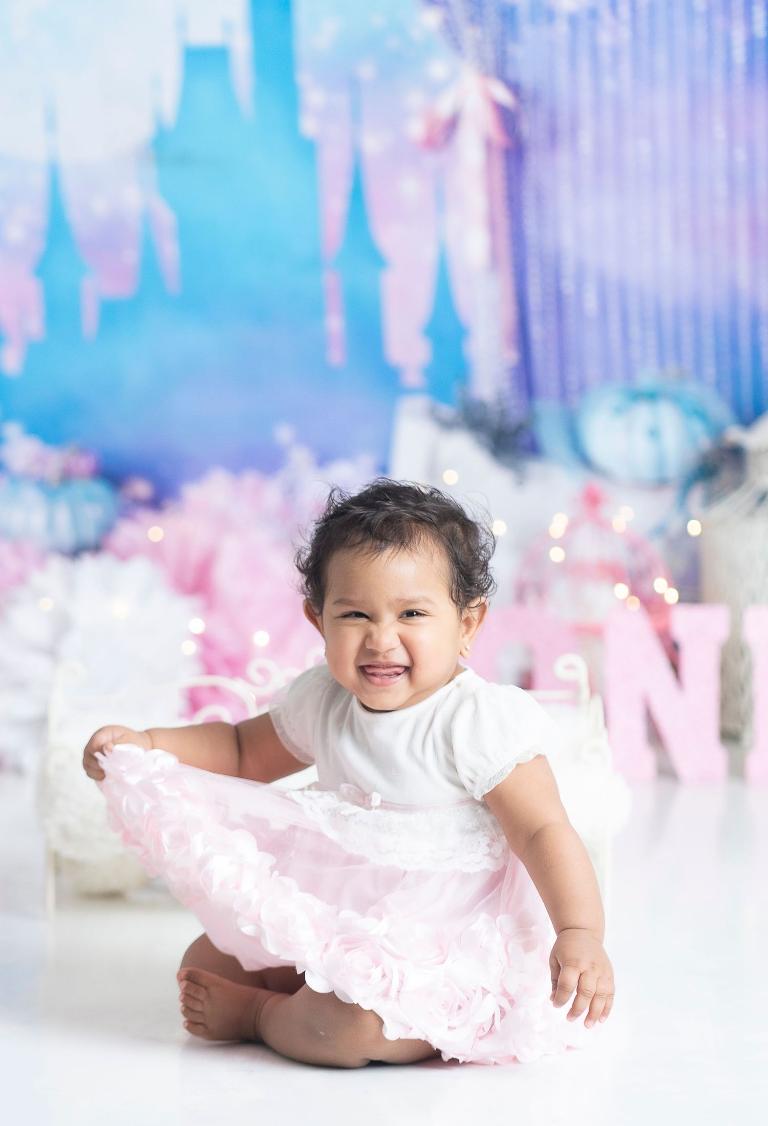 Dreamy castle-themed photoshoot with white and pink tulle dress against blue fantasy backdrop.