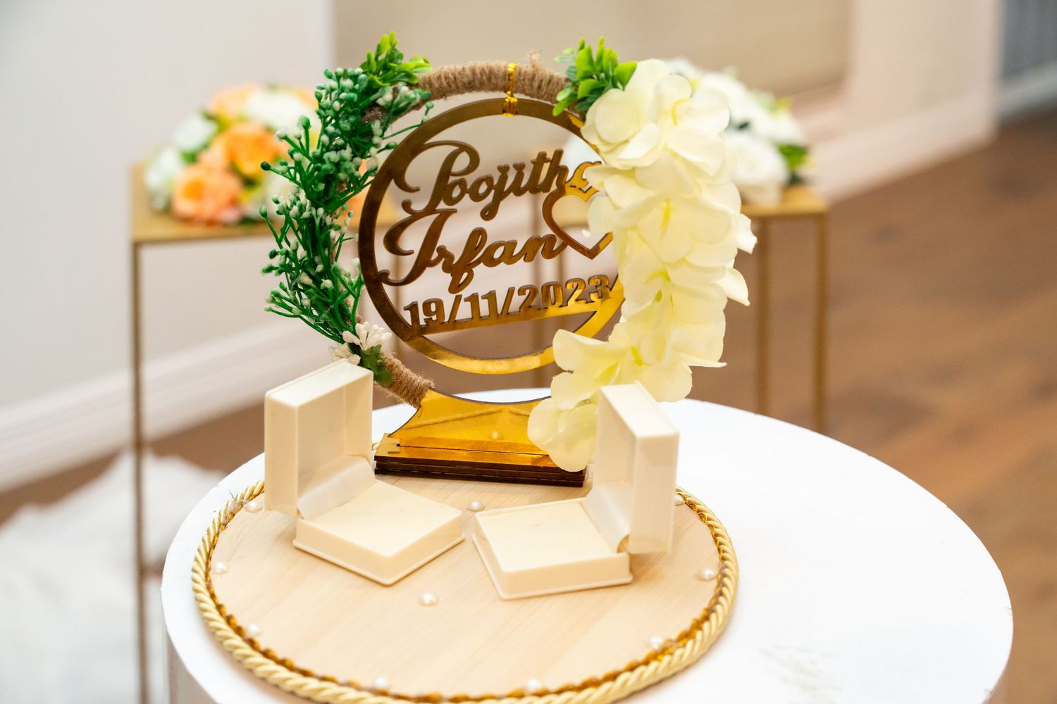 Elegant wedding cake topper with floral accents displayed on white and gold stand.