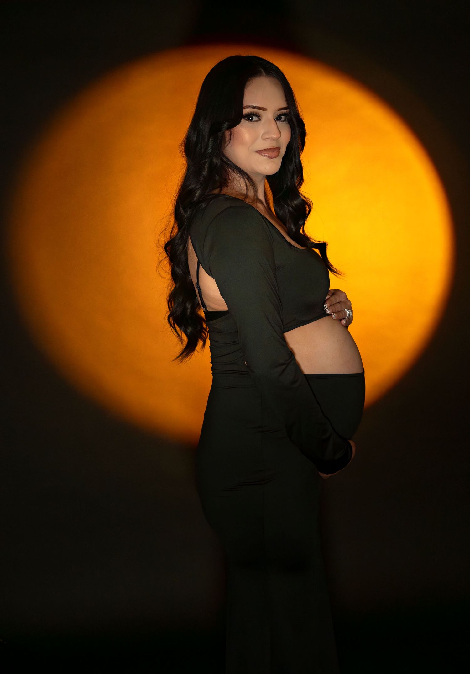 Artistic portrait series with dramatic orange lighting and dark clothing creating moody atmosphere.