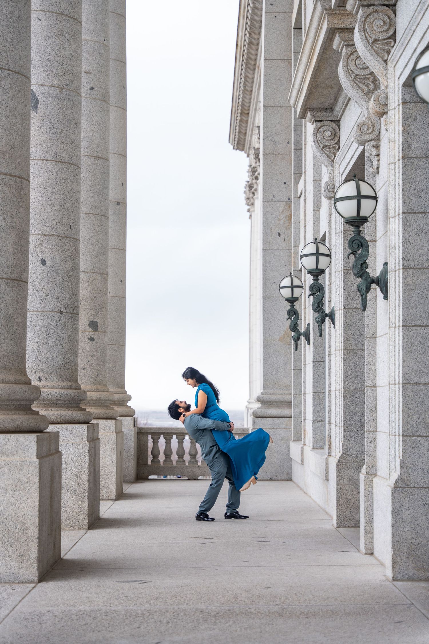 Couple embracing in dramatic pose under classical columned architecture.
