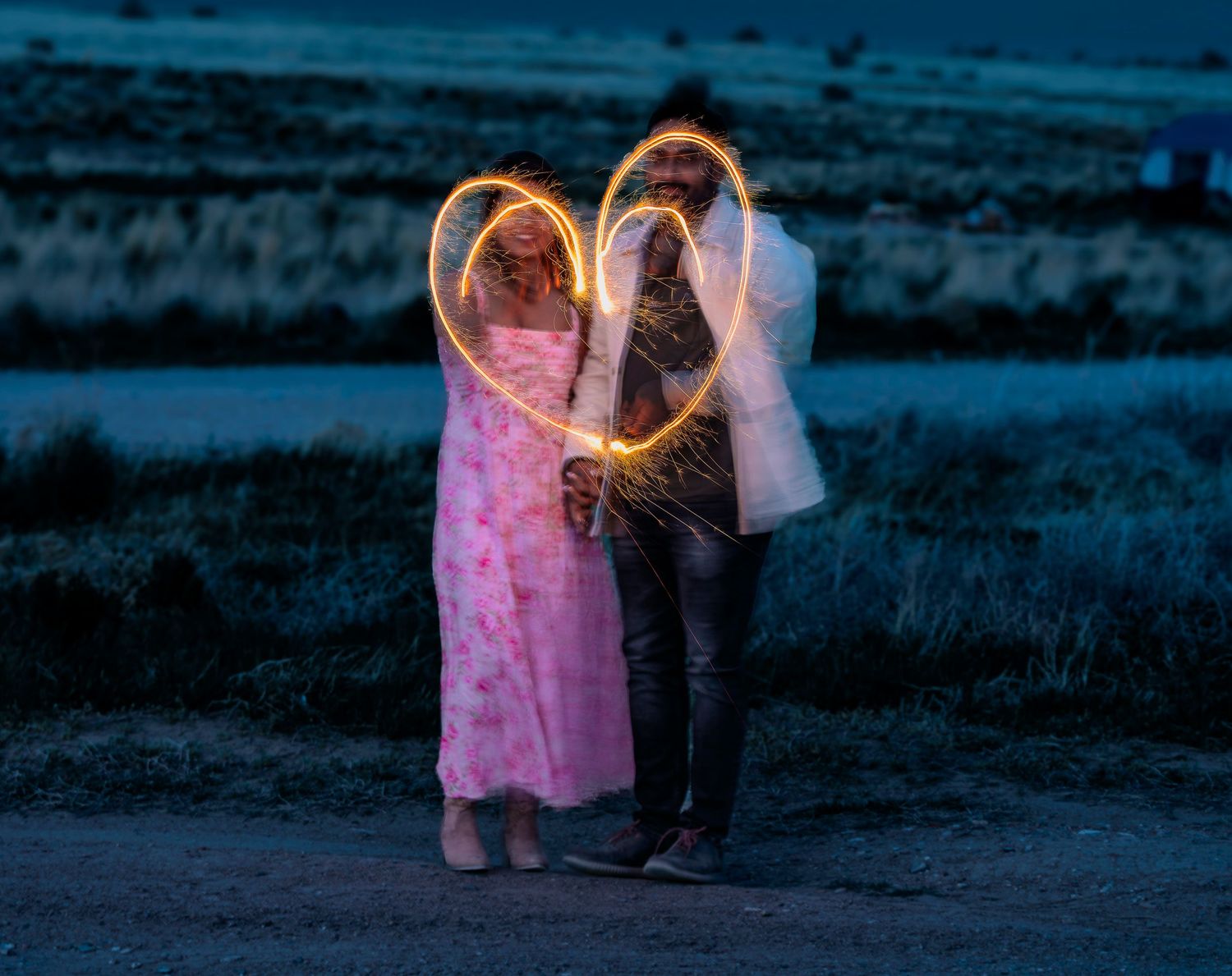 A couple dances together at dusk in a romantic pink-tinted setting.