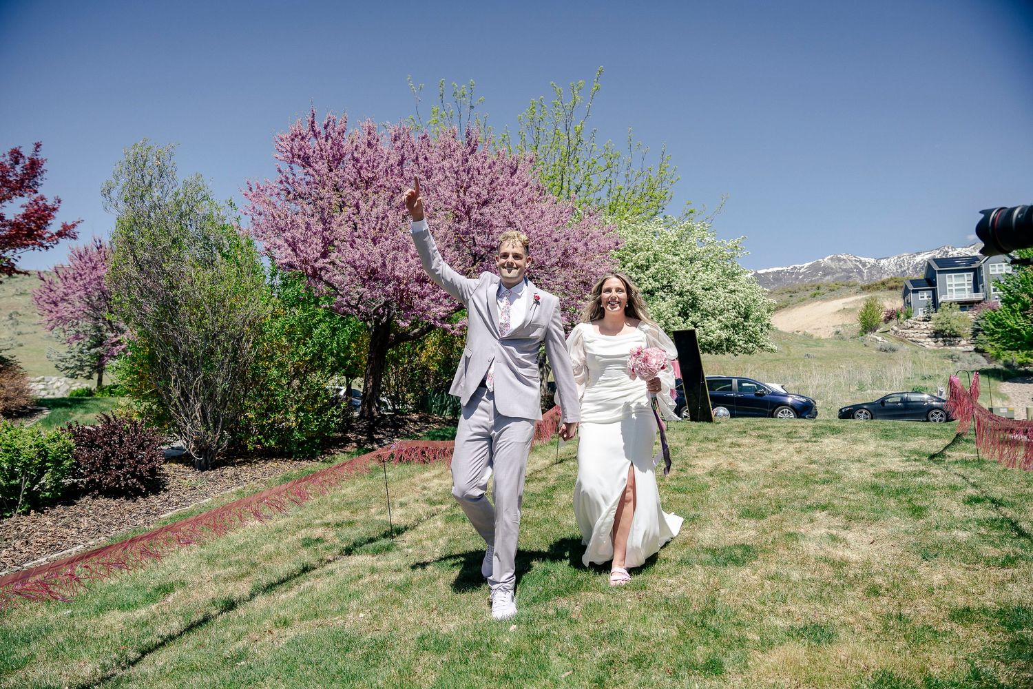 A couple walks hand in hand through a spring garden with blooming cherry trees.