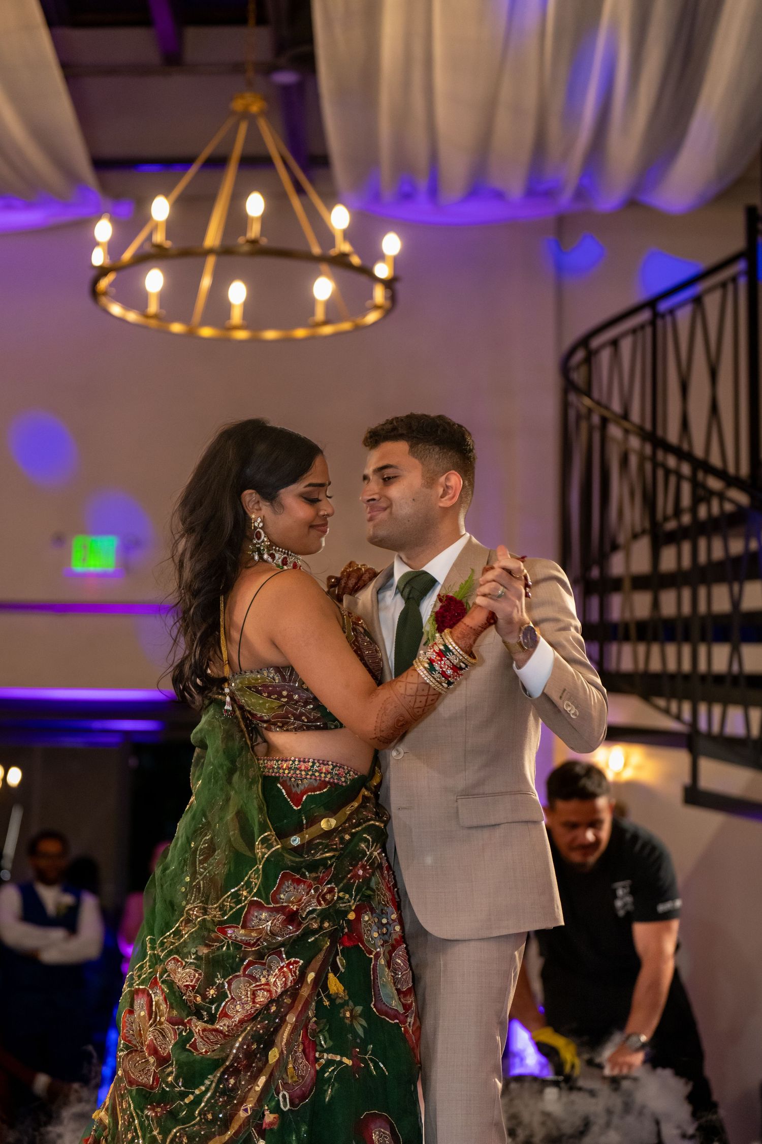 Couples first dance captured under ornate chandelier at indoor wedding reception.