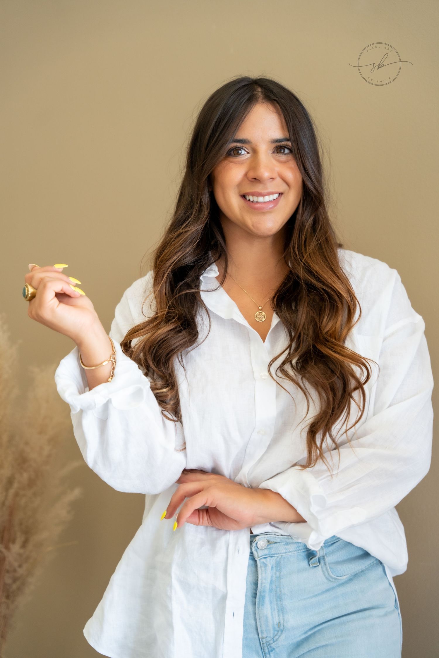 A casual portrait featuring a white button-down shirt and light denim in a minimal studio setting.