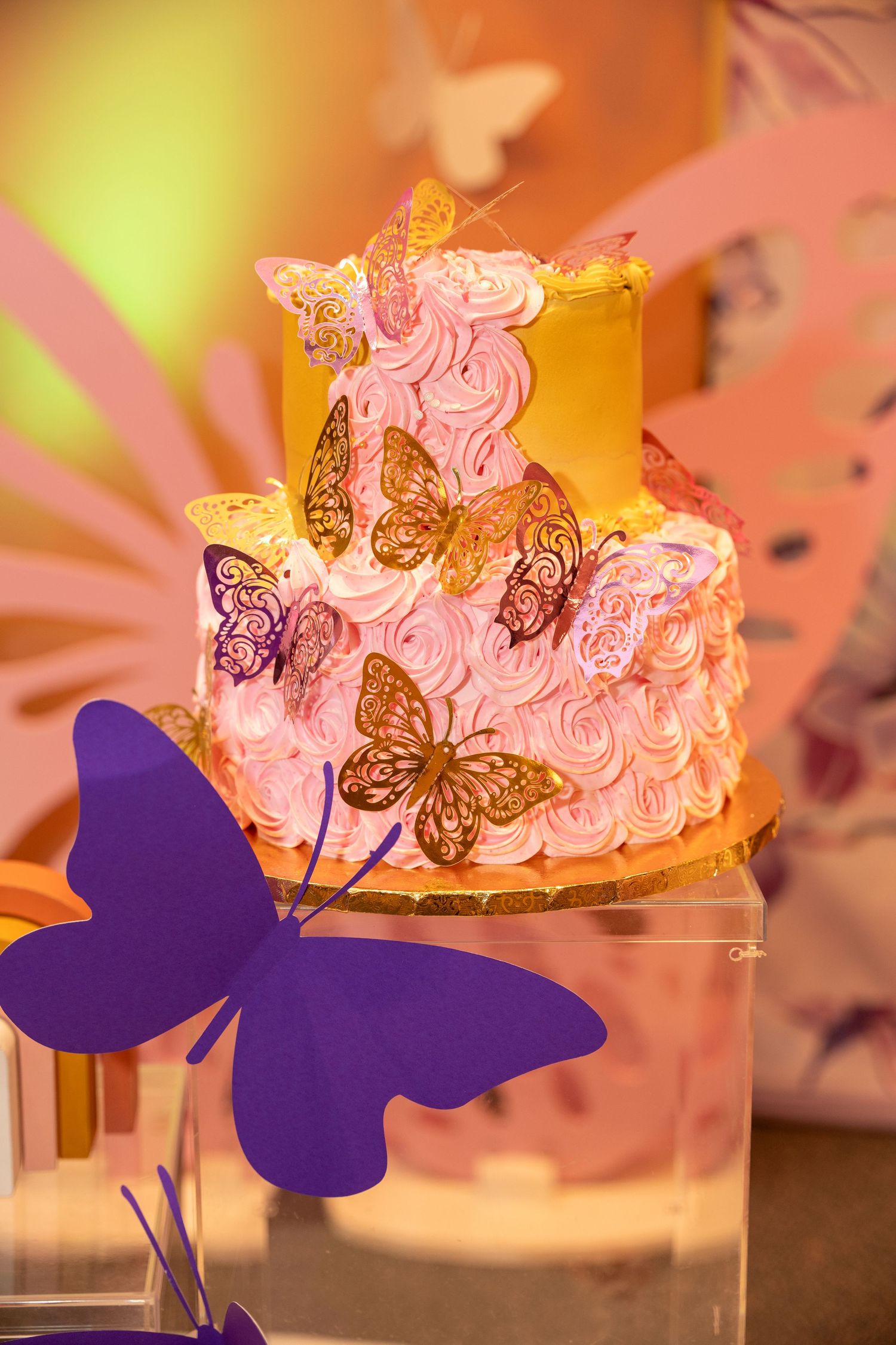 Pink birthday cake decorated with golden butterfly accents and purple butterfly silhouette.