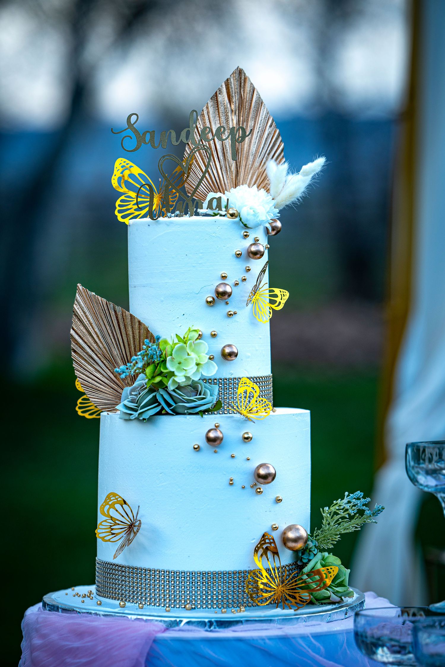 Light blue wedding cake decorated with metallic butterflies and silver accents.