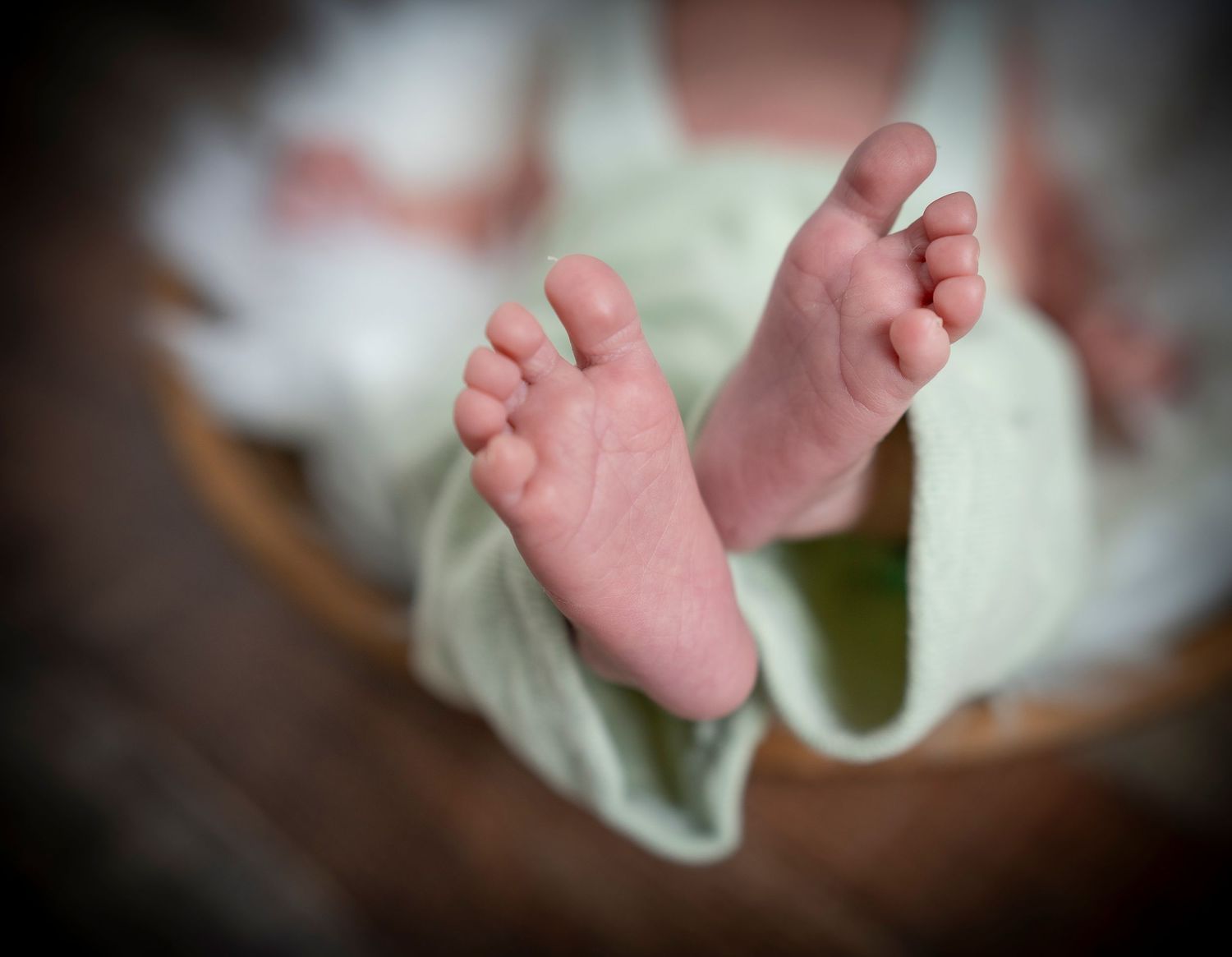 Close-up of tiny newborn feet in mint green fabric.