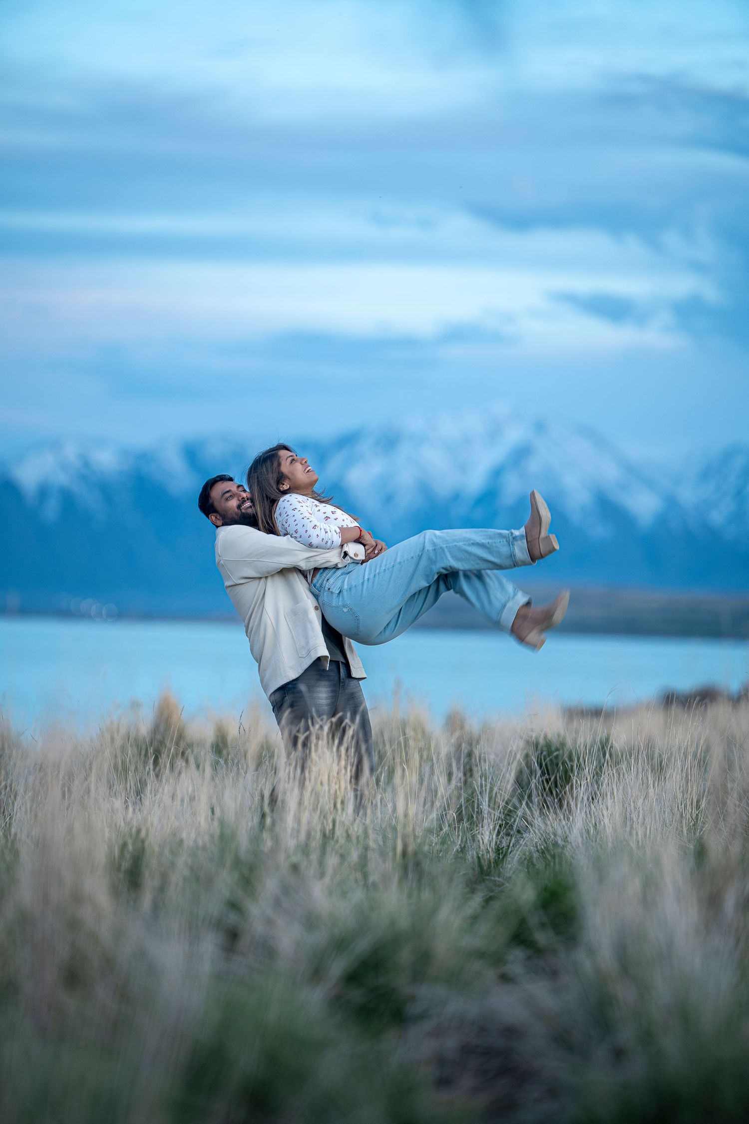 A couple performs fun acrobatic poses in a field of tall grass.