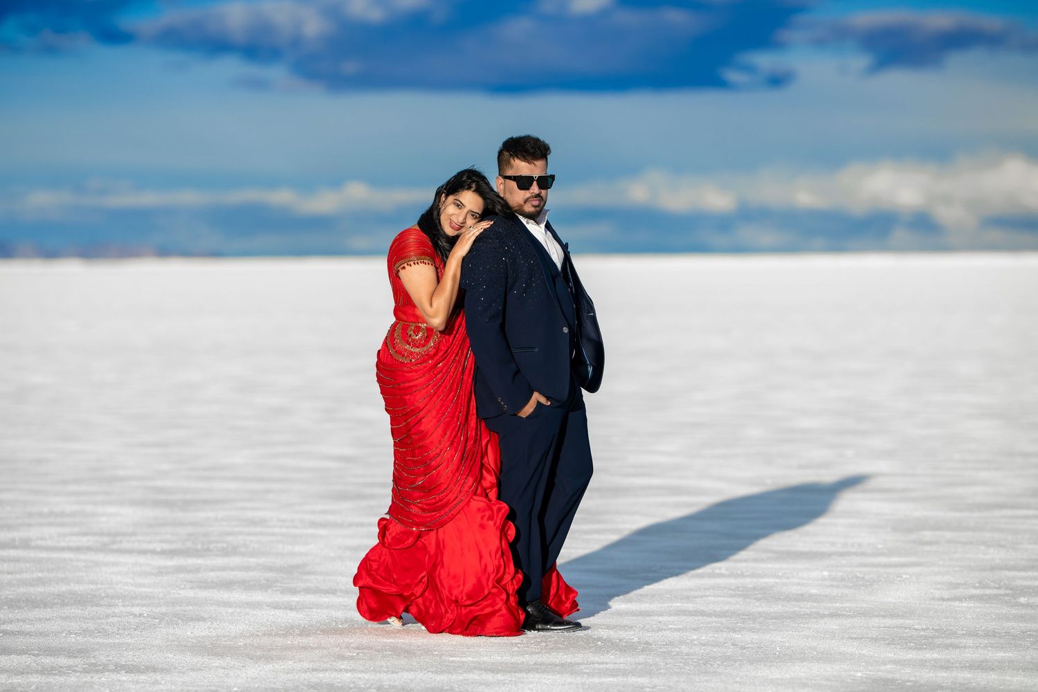 Couple in formal attire posing on Bonneville Salt Flats with dramatic red dress.