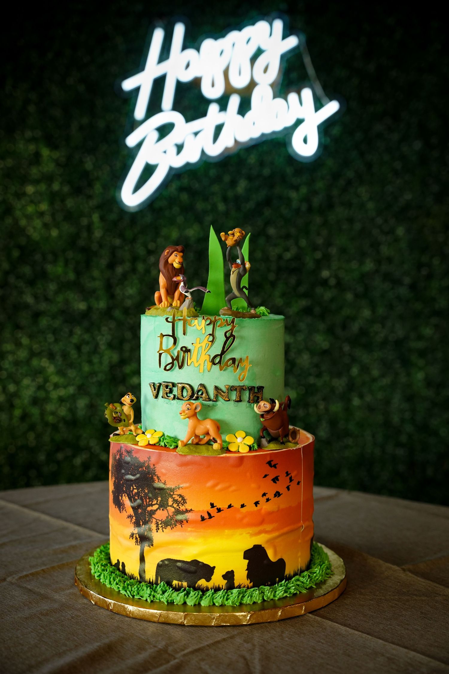 Lion King themed birthday cake with safari silhouettes and LED Happy Birthday sign.