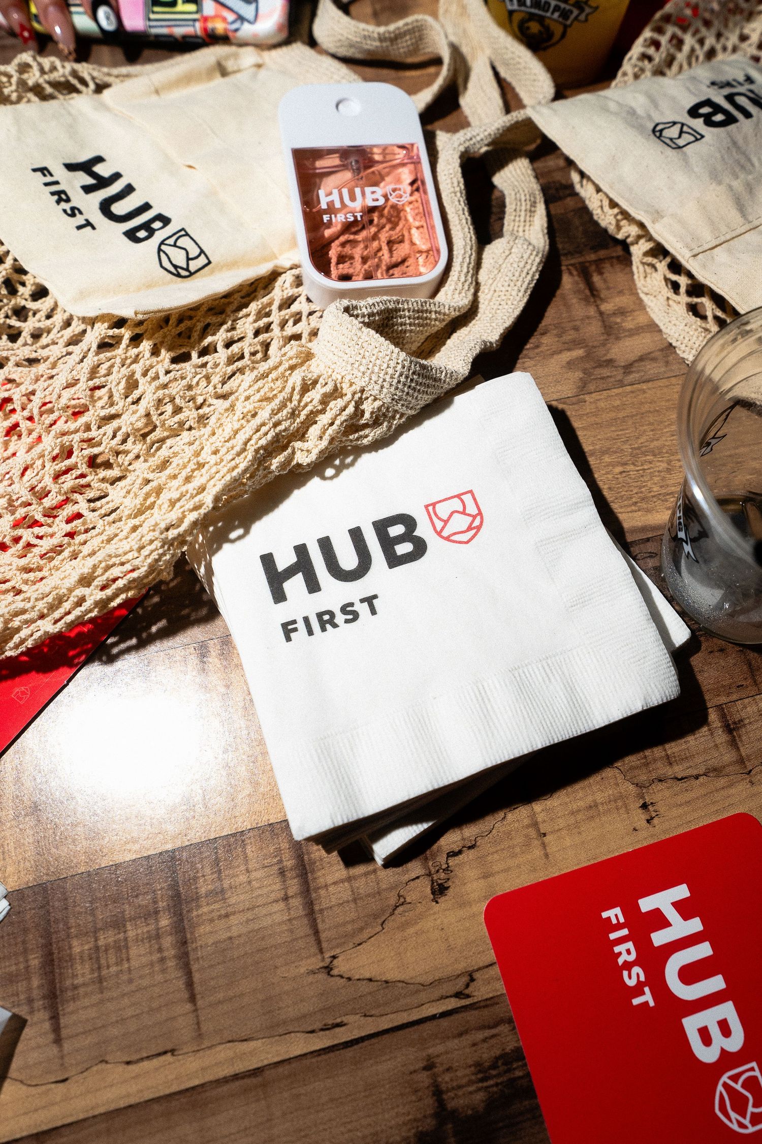 Hub First branded napkins, tote bags, and merchandise displayed on wooden table at event.