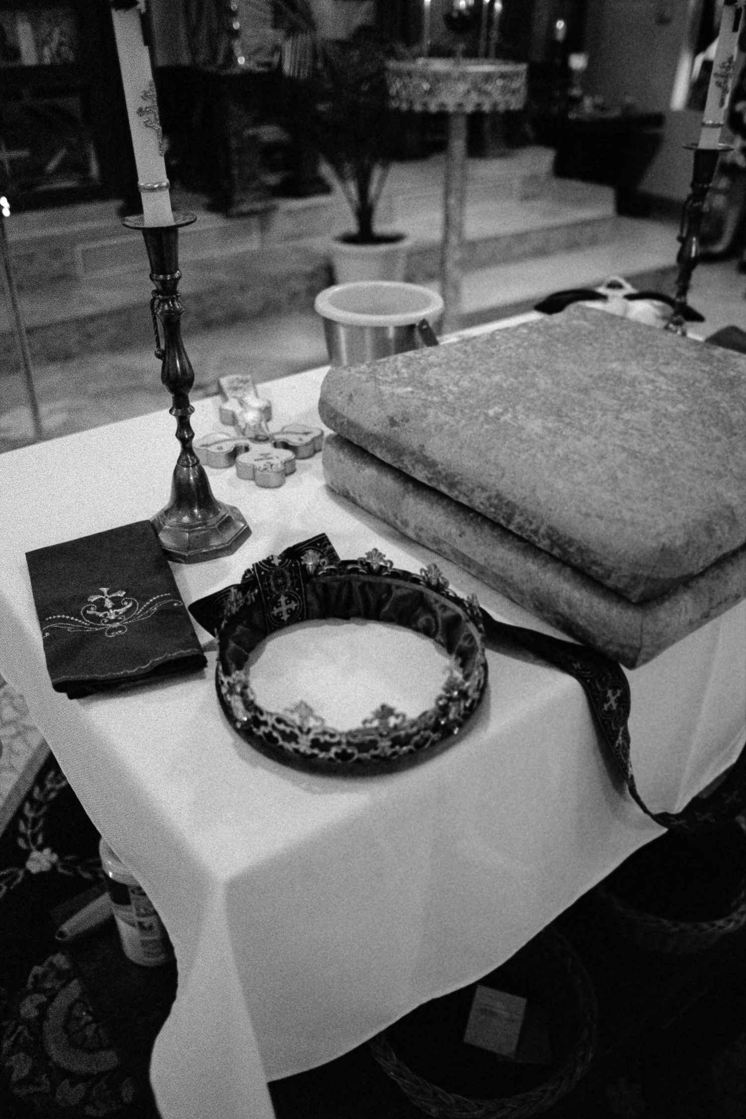 Black and white photo of orthodox wedding crown and candle on a ceremonial altar table.