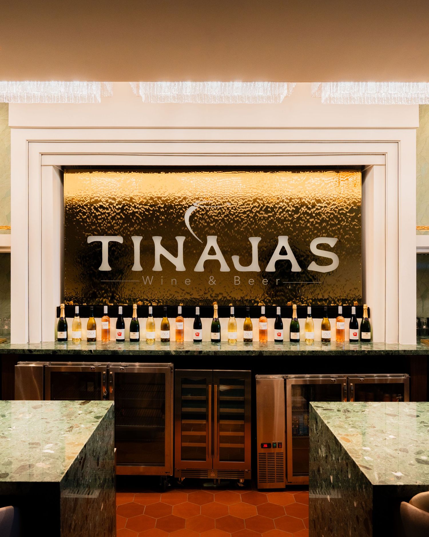 Tinajas Wine and Beer bar featuring backlit signage, wine bottles display, and green marble countertops.