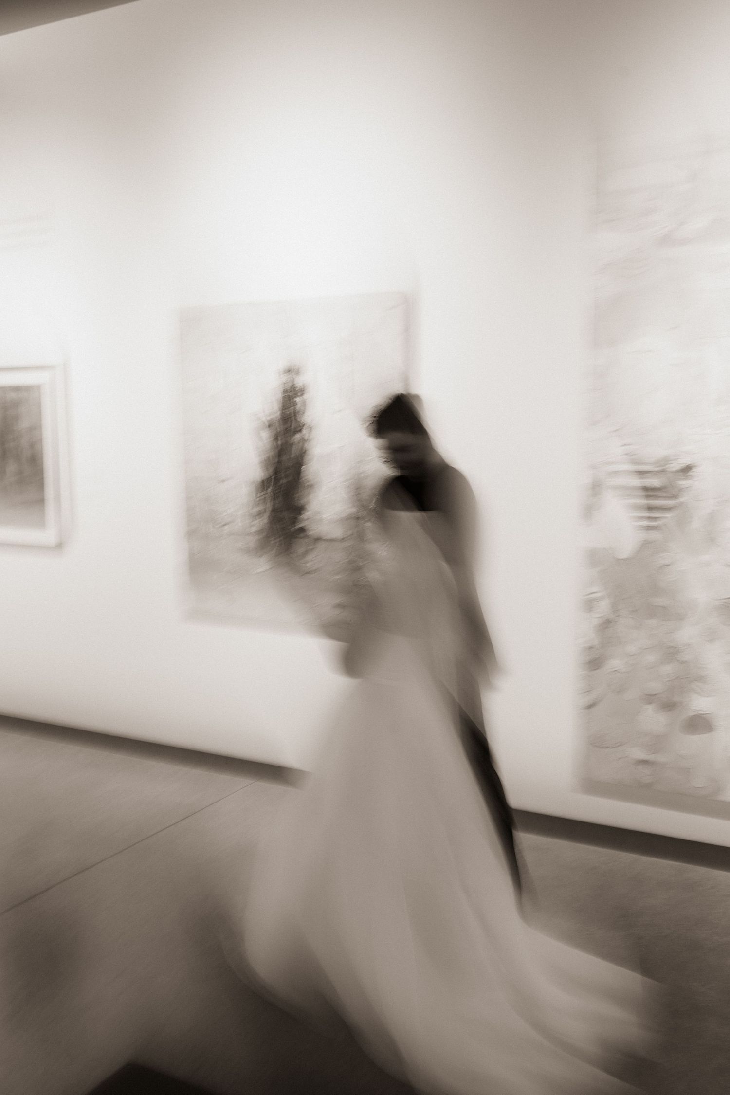 Artistic blurred motion photo of bride and groom walking through an art gallery on their wedding day.