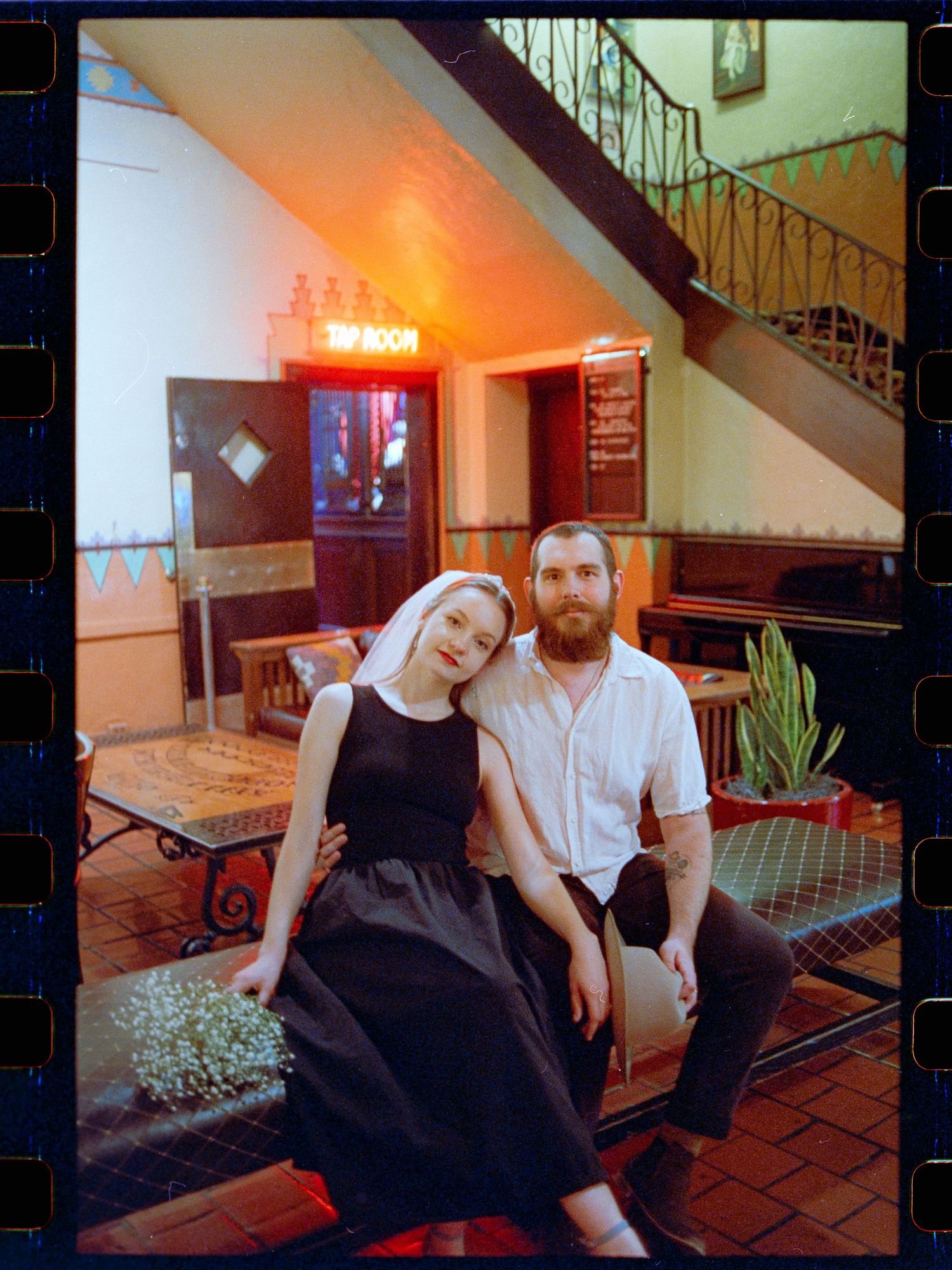 Smiling wedding couple posing inside vintage Hotel Congress lobby with neon Top Room sign.