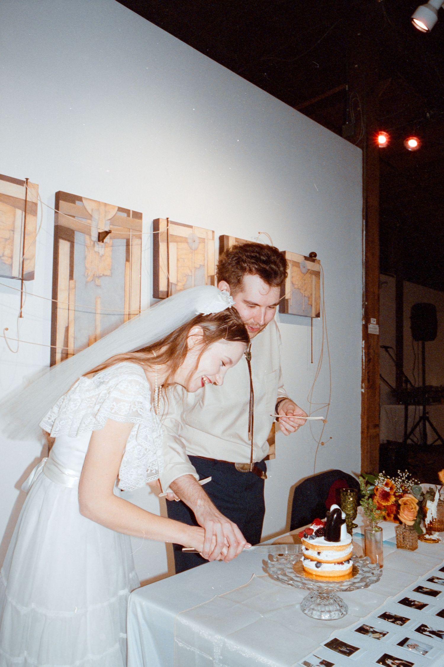 Bride and groom cutting their wedding cake together at reception venue.