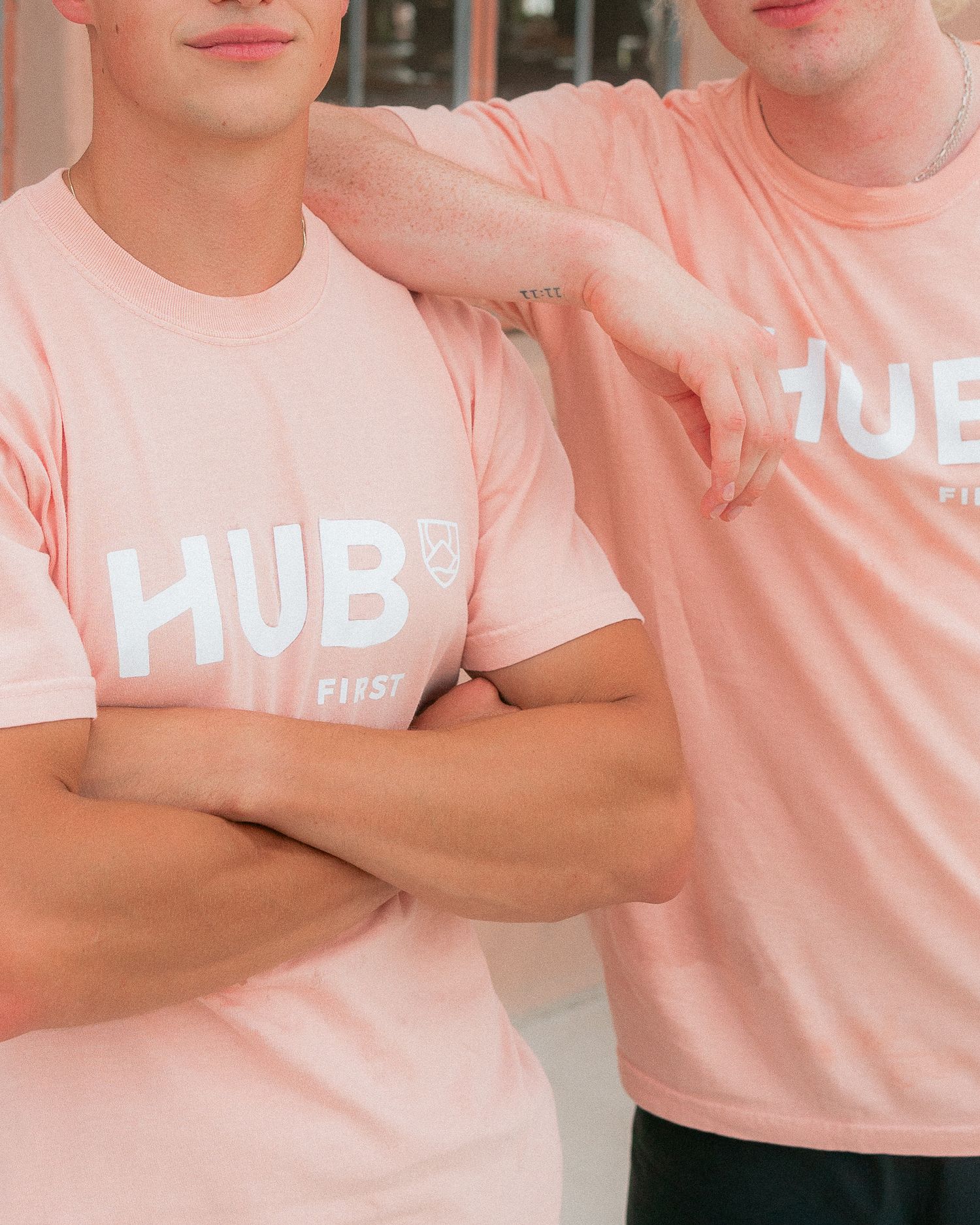 Two young men wearing pink Hub First branded t-shirts posing together outdoors.