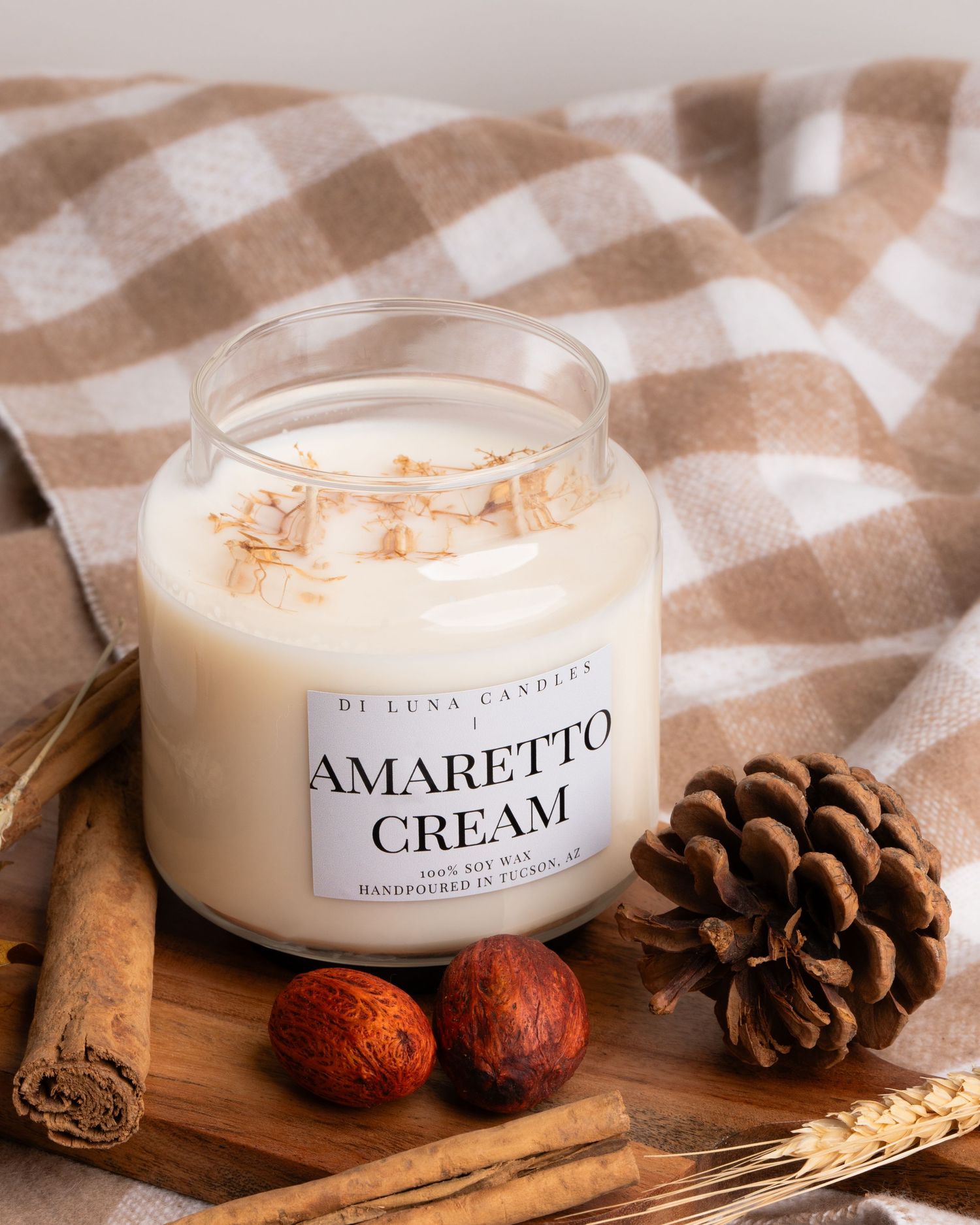 Di Luna Candles Amaretto Cream soy wax candle in glass jar with cinnamon sticks and pine cone.