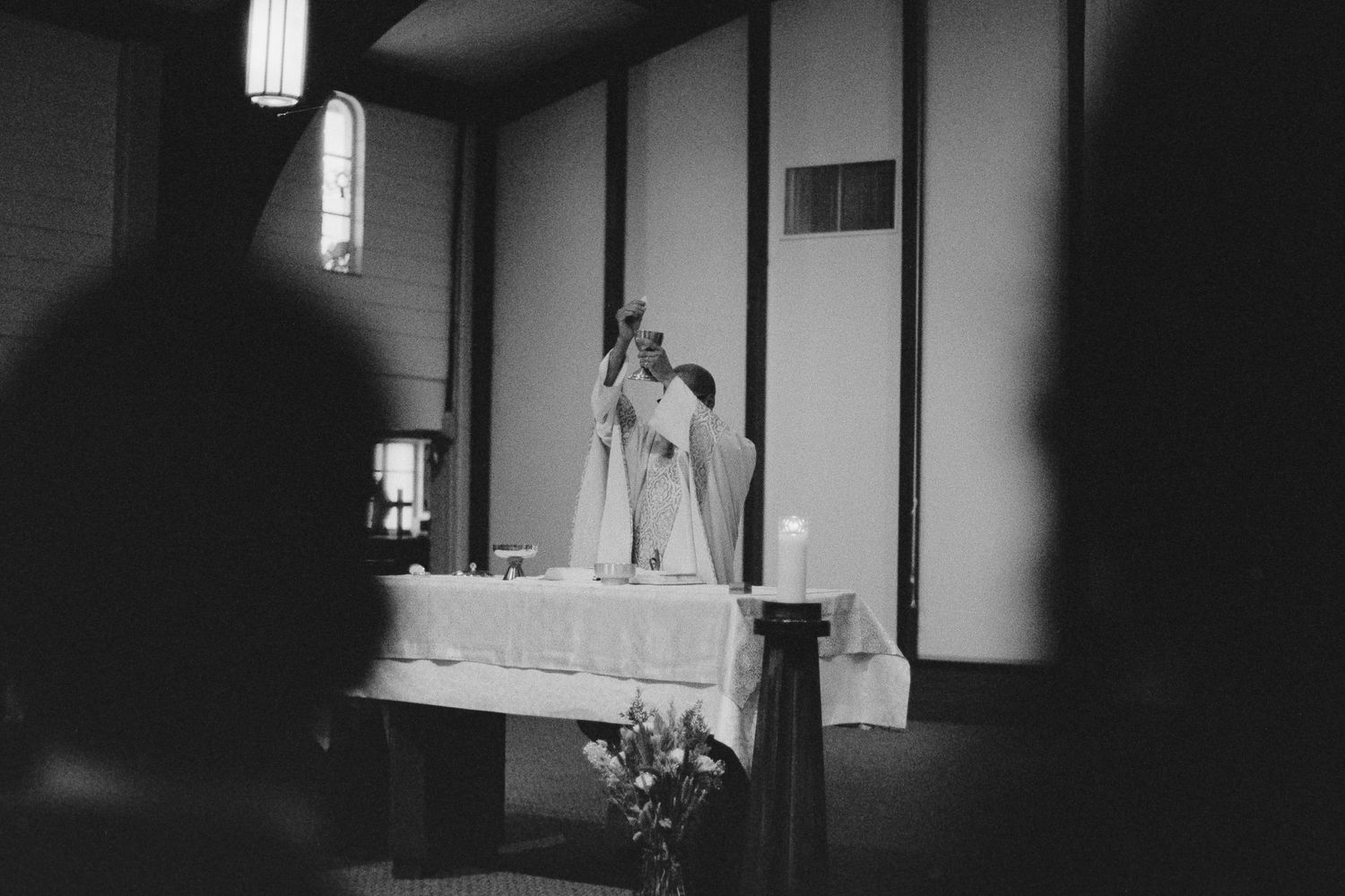 Black and white photo of priest performing wedding ceremony at church altar.