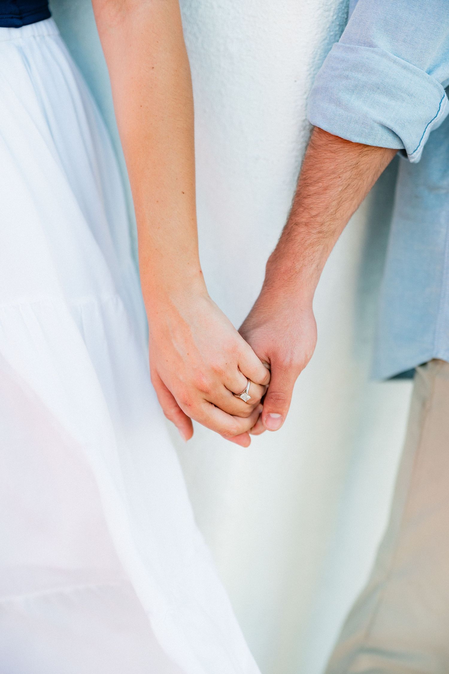 Close-up of engaged couple holding hands, showcasing a sparkling diamond engagement ring.