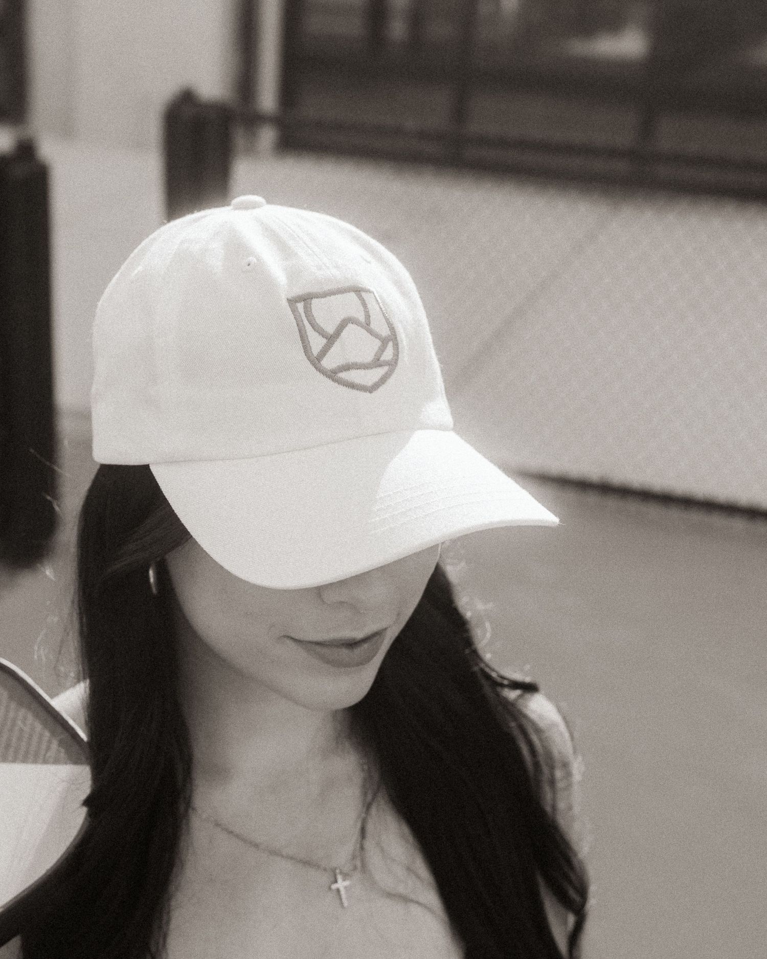 Woman wearing a white Hub First logo cap in black and white photo on a tennis court.