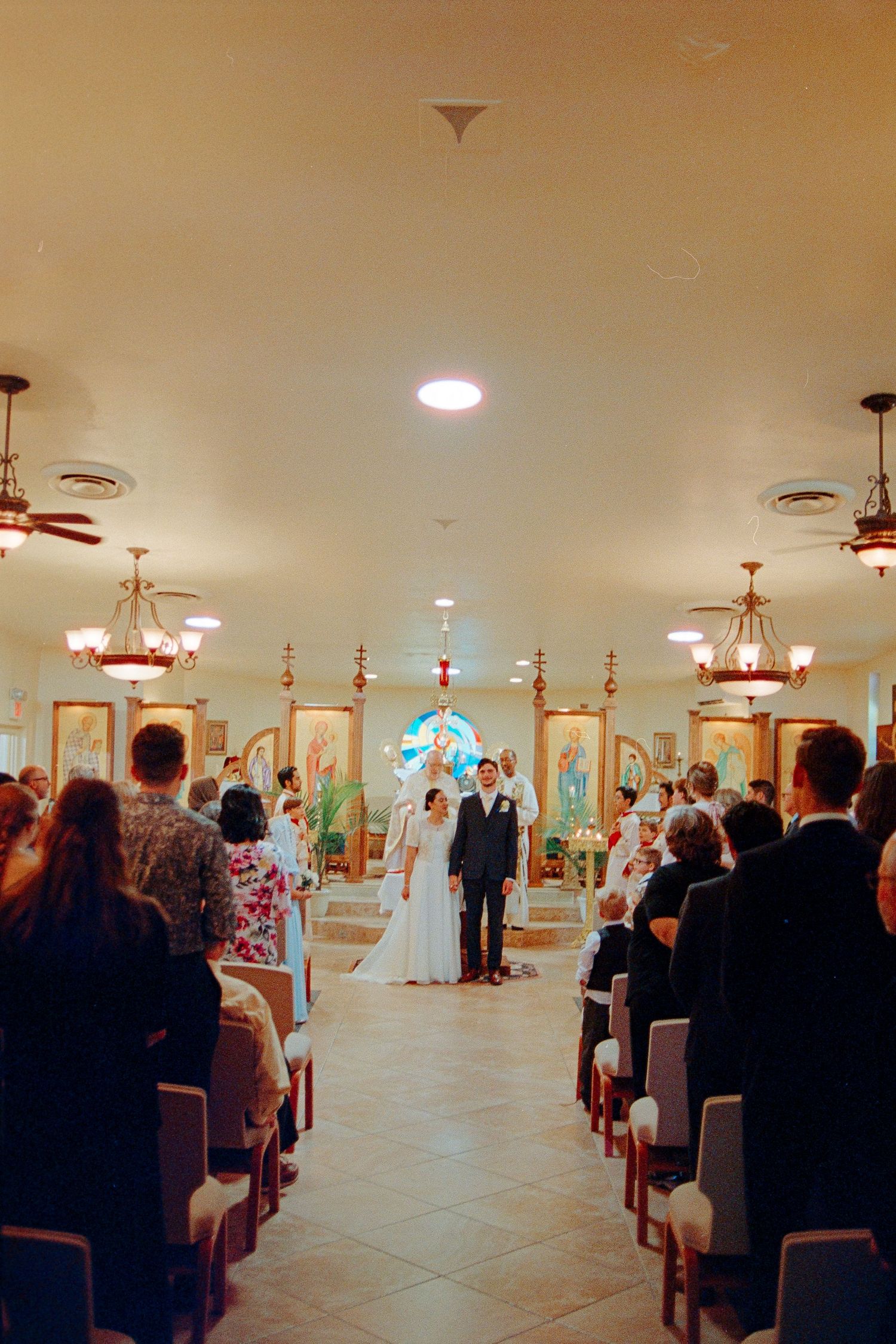 Bride and groom stand at the altar of a warmly lit church during their wedding ceremony.