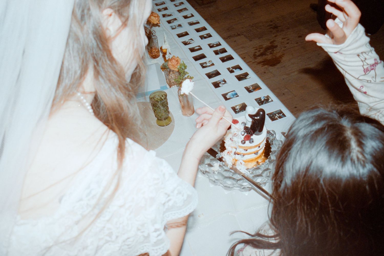 Bride examining wedding cake and photo strips on table at reception.