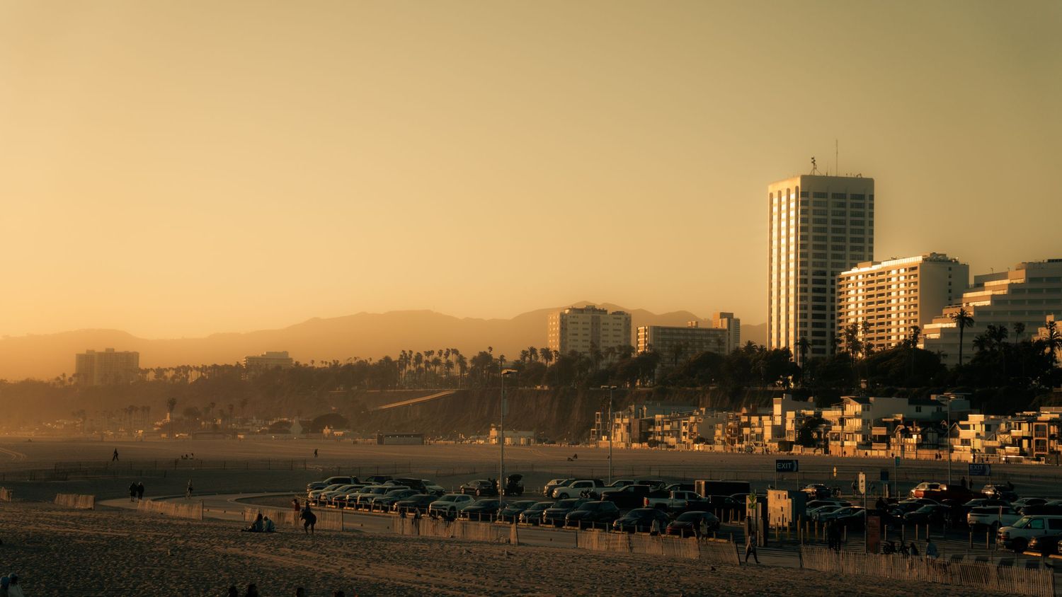 Warm-toned panoramic view of a coastal city skyline at dusk.