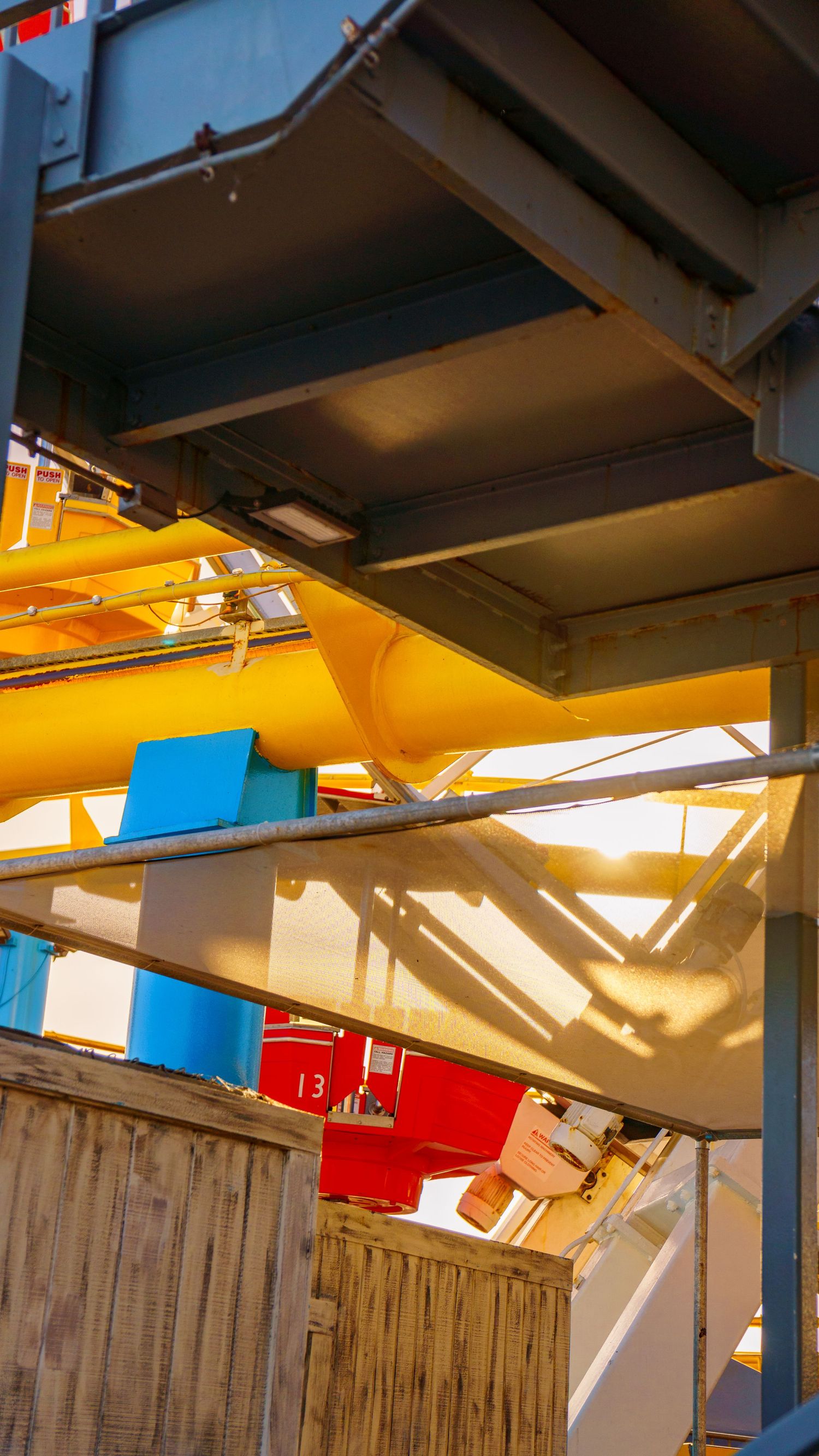 Abstract architectural detail of wooden panels and yellow beams under dramatic lighting.