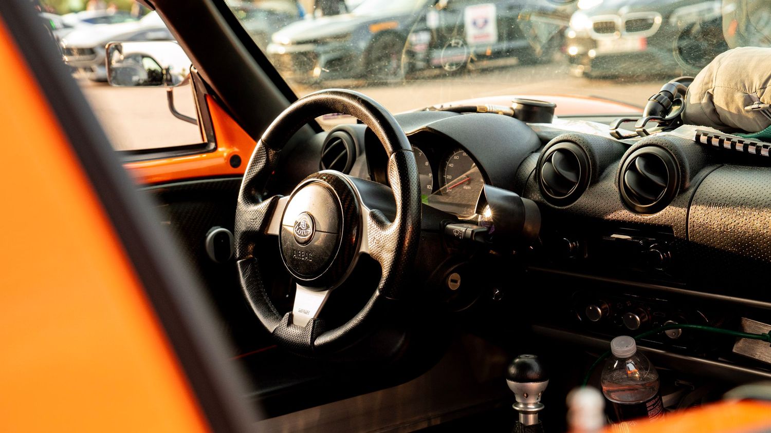 Interior of orange Lotus sports car showing modern dashboard and steering controls.