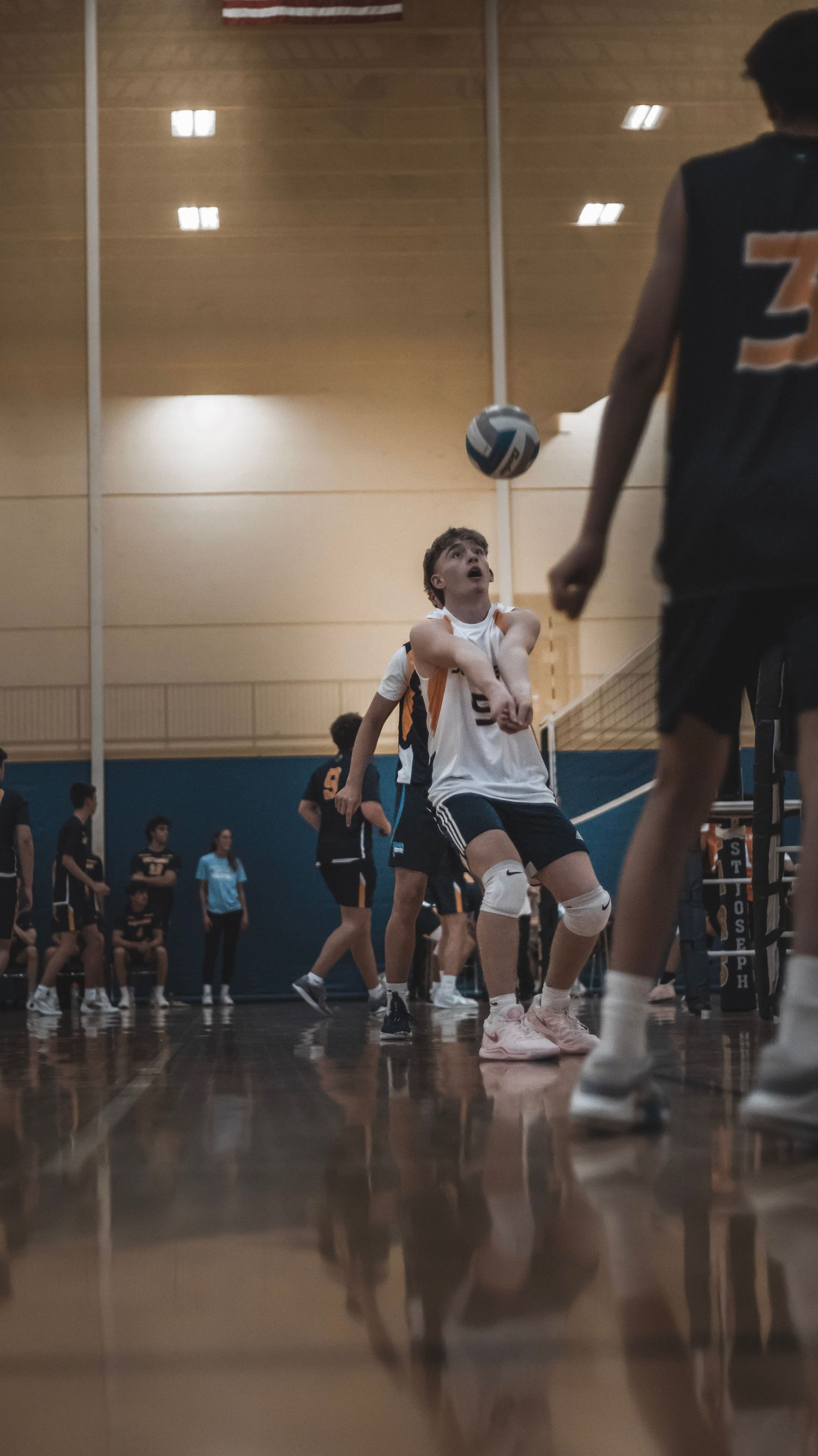 A player in white prepares to hit the volleyball during an indoor game.