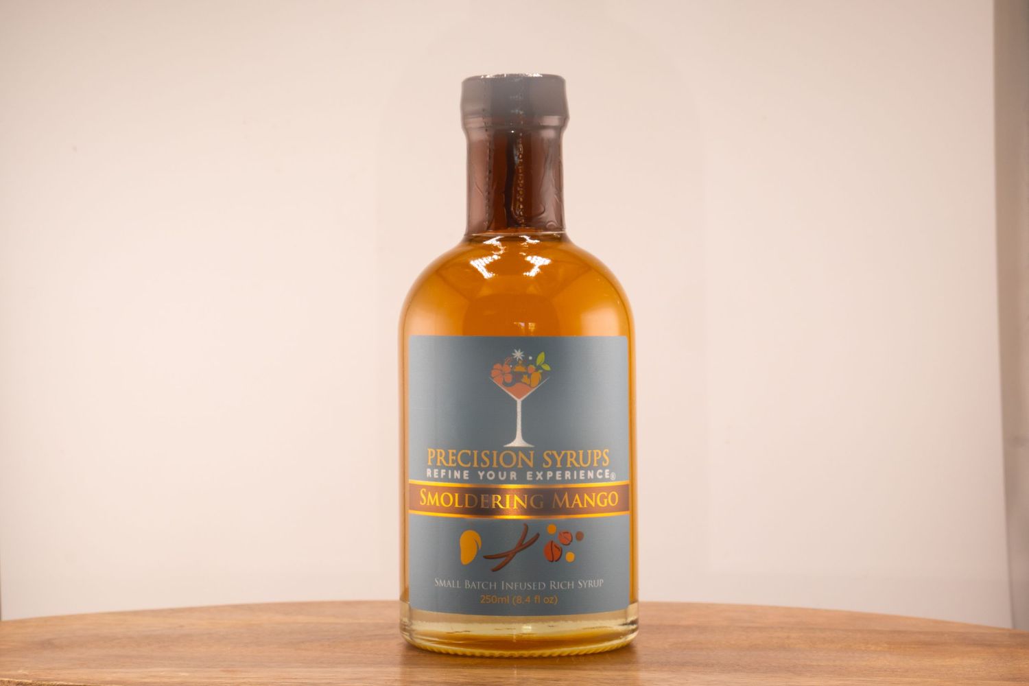 A bottle of premium amber spirits with a tree logo and gray label on wooden surface.