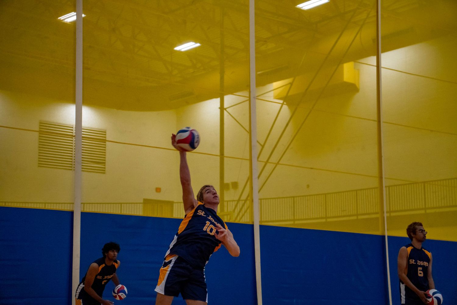 Player in navy uniform reaches high to spike the volleyball during an intense game.