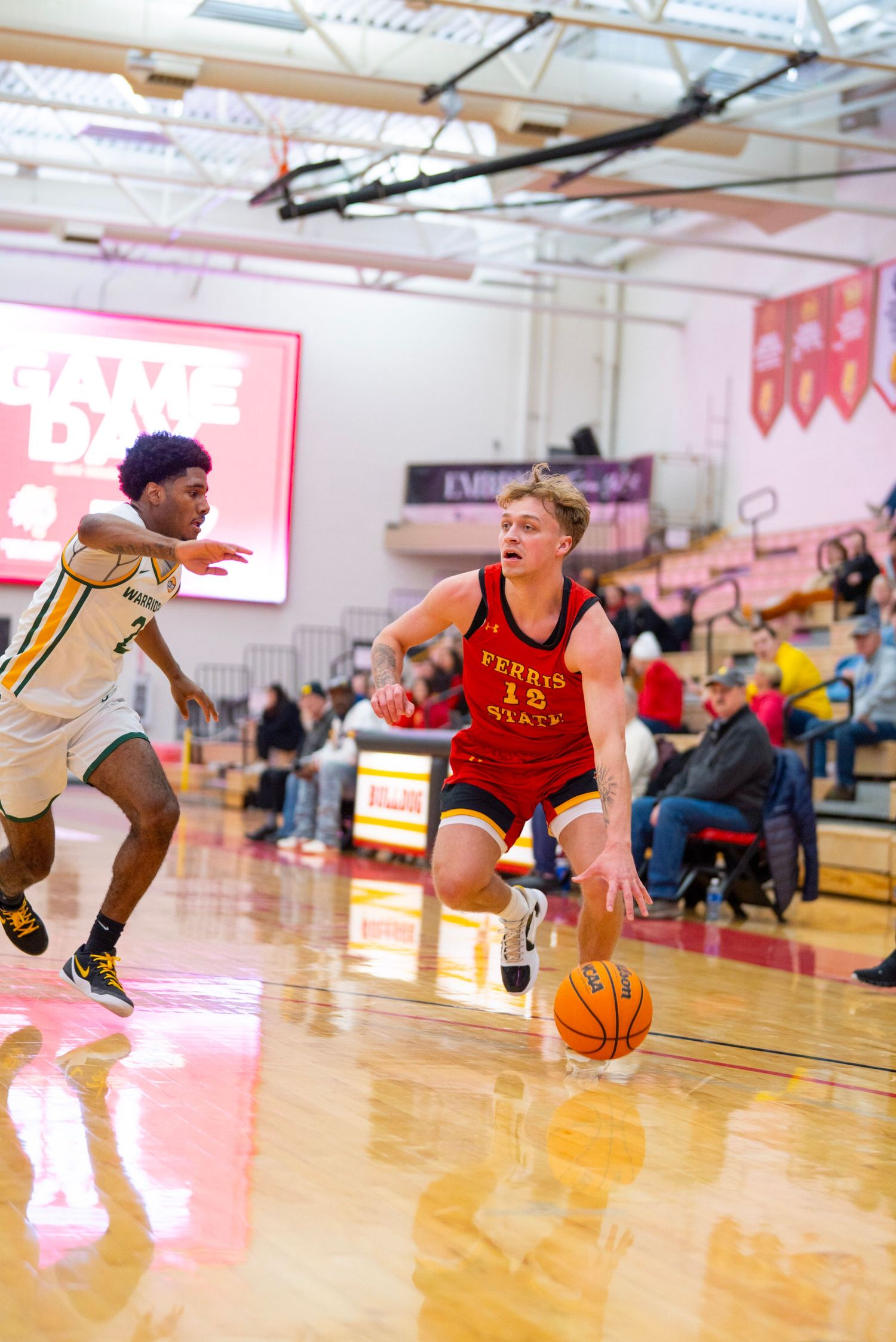 Basketball players compete on a shiny wooden court during an intense indoor game with spectators watching.