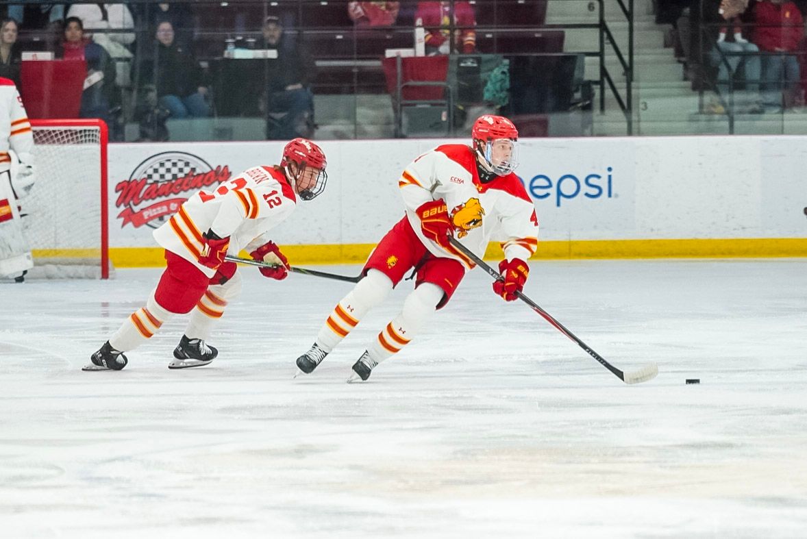 Hockey players in red and white jerseys chase after the puck during an intense game on the ice.