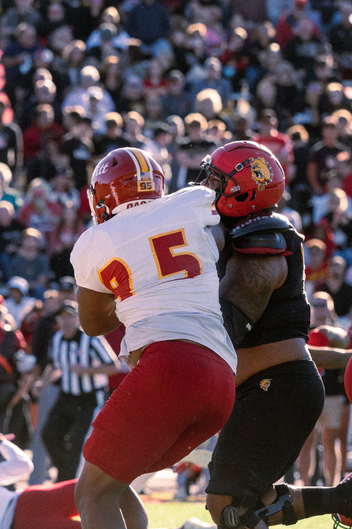 Football player in red jersey tackles opponent in black uniform during a competitive game.