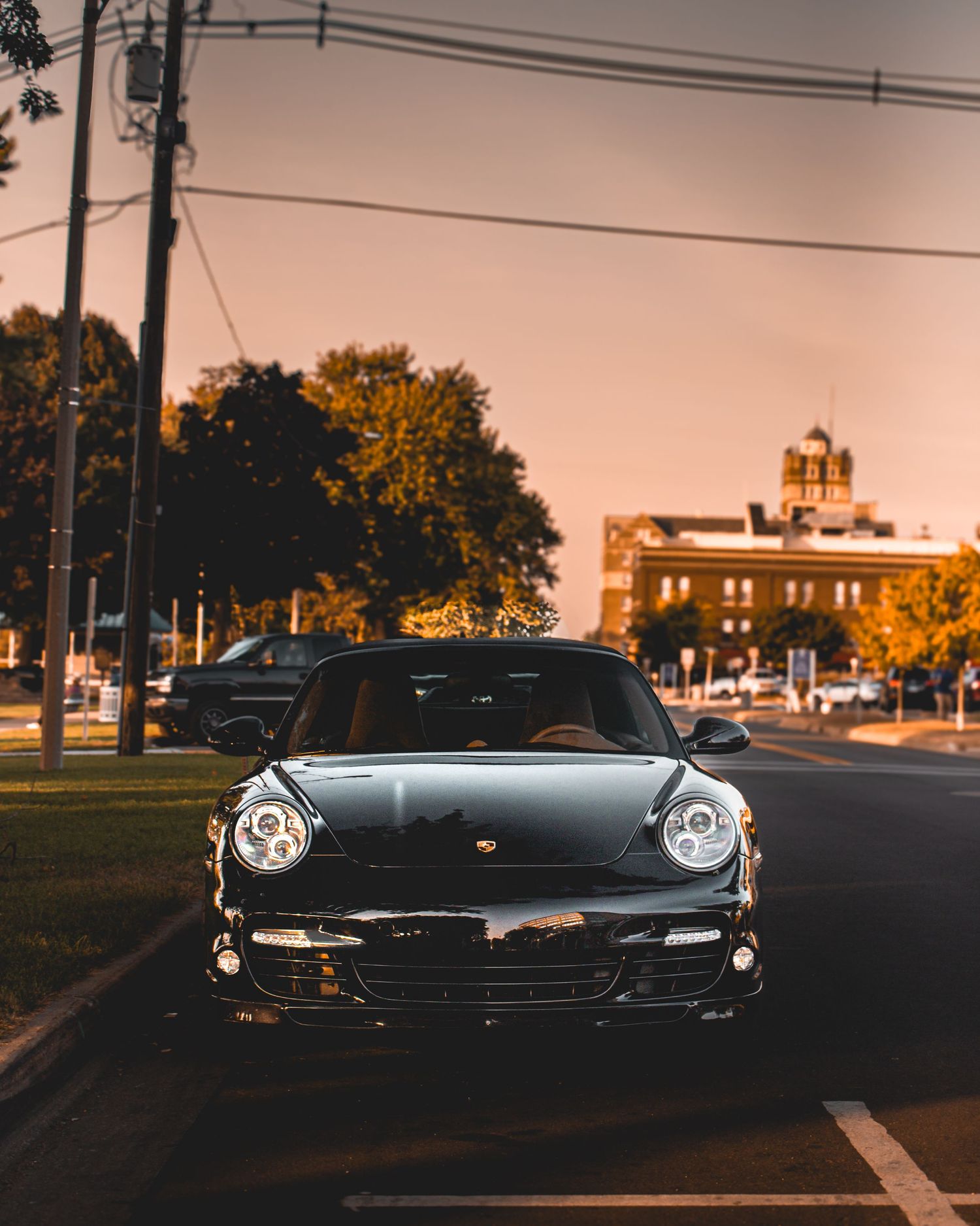 Black Porsche 911 photographed from front at dusk with urban backdrop.