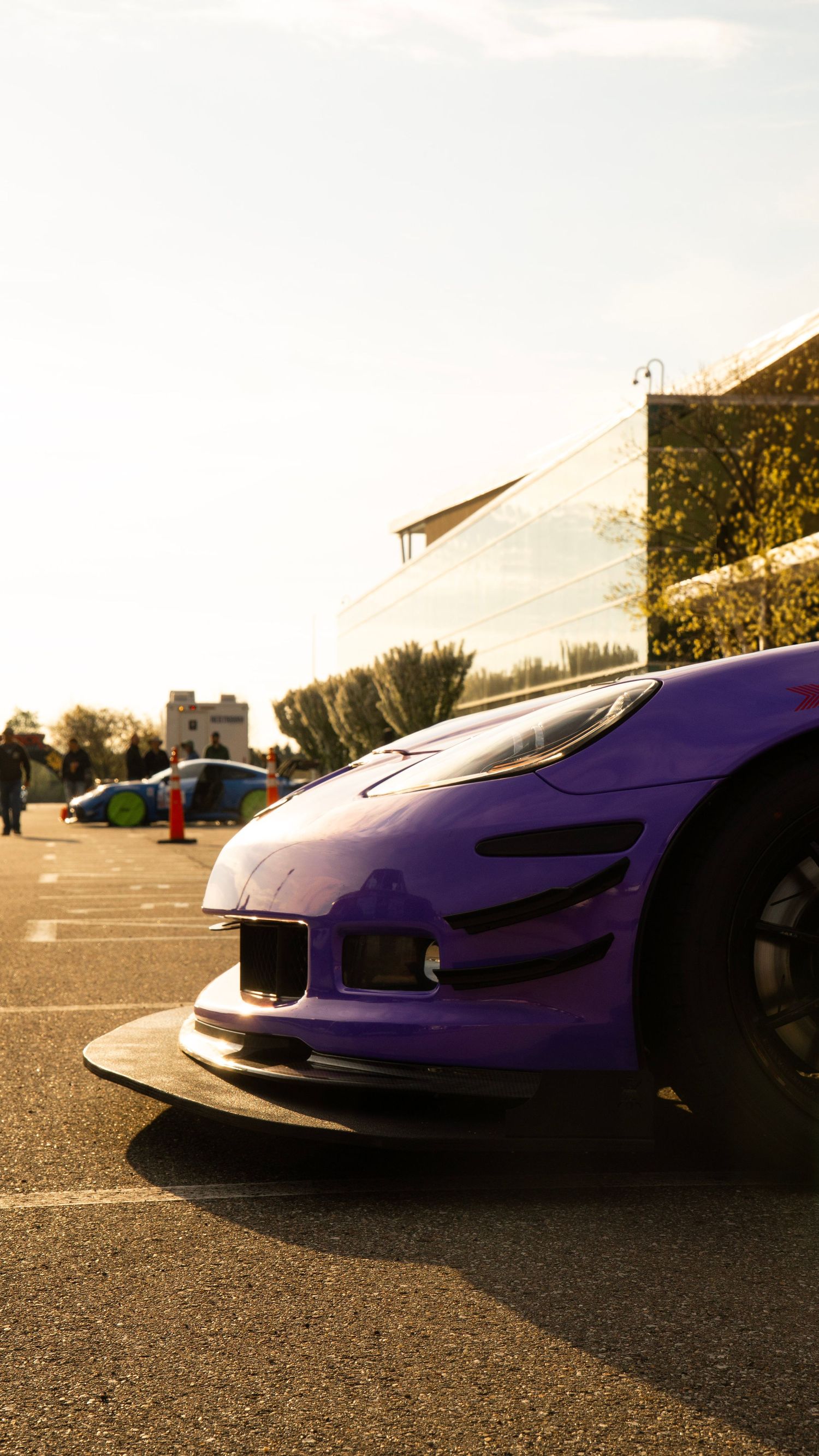 Low angle view of purple sports car front end against bright background.