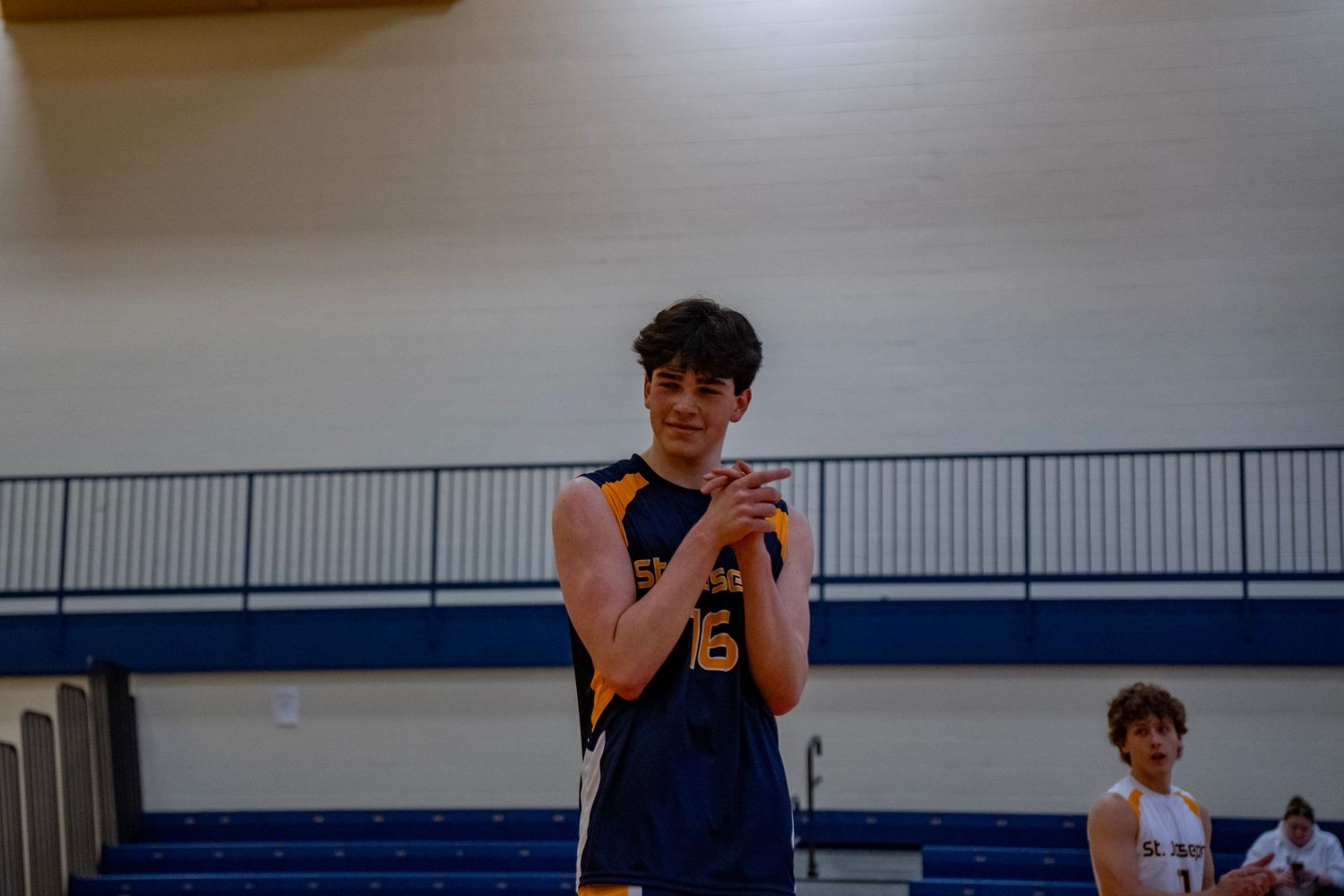 A volleyball player in a navy uniform stands ready on the court.