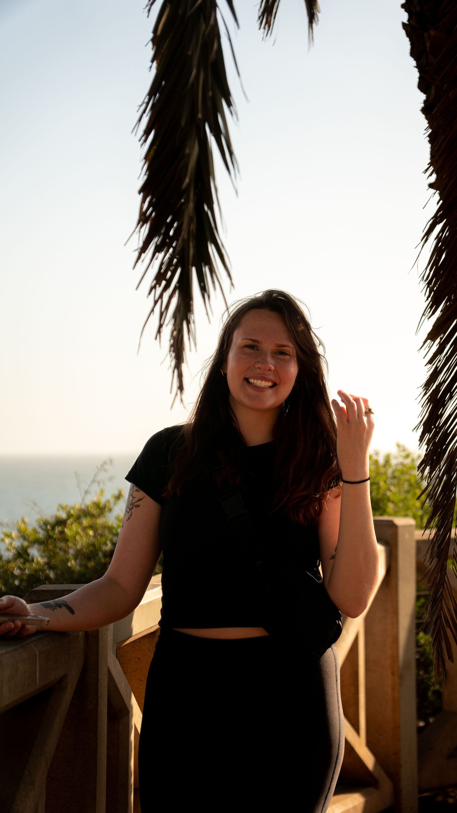 Joyful portrait against ocean backdrop with palm trees framing the scene.