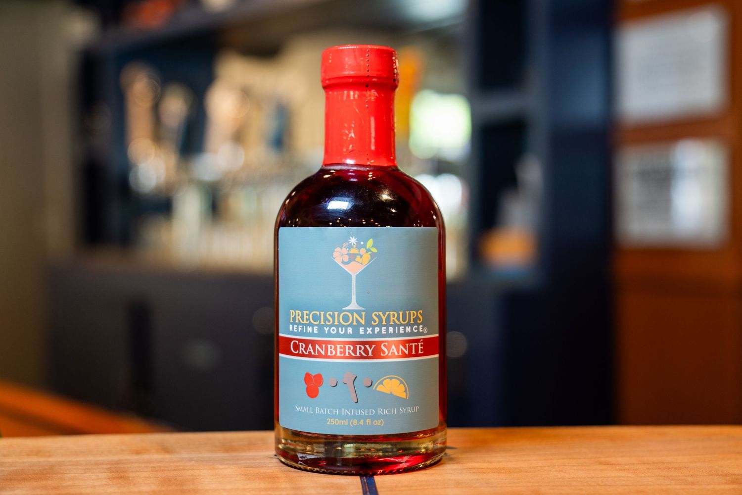 Bottle of Precision Syrups with red cap on wooden surface.